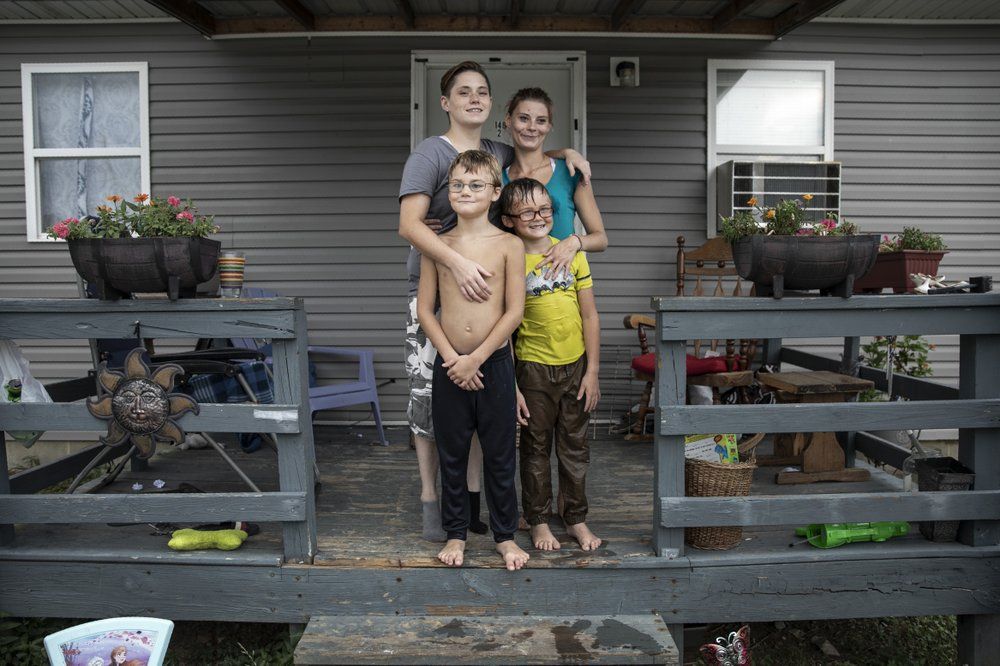 Tasha Lamm, 30, right, poses for a photo with her girlfriend, Alicia Mullins, 22, and Lamm's sons, Donovyn, 8, left, and Gabriel Bonice, 7, in front of their home in Bidwell, Ohio, on Monday, July 27, 2020. "It sucks being poor," says Lamm who is raising her two sons on public assistance. A high-school dropout, she has been promising herself for years that she'd get her equivalency degree. Image by Maye-E Wong/AP Photo. United States, 2020.