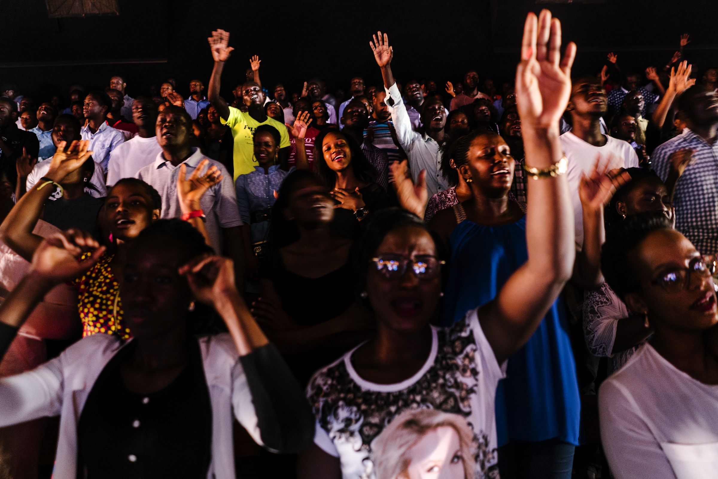 Worshippers sing during a Sunday service at Watoto church, an English speaking Pentecostal church, in downtown Kampala. Activists say Watoto, led by American pastor Gary Skinner,  has been instrumental in spreading homophobia, including through hosting American evangelical Scott Lively. Image by Jake Naughton. Uganda, 2017.