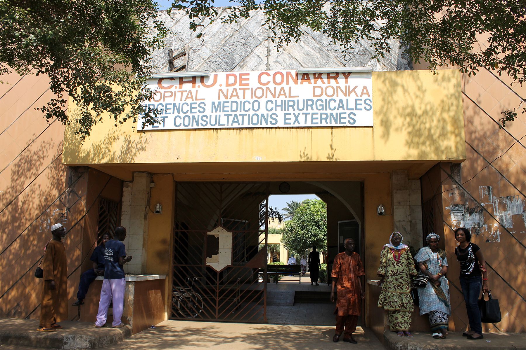 Here, we see the entrance to Donka National Hospital in Conaky, the capital of Guinea. Since the government only commits 4.7 percent of its budget to health, many hospitals and clinics, like this one—the largest government hospital in the country—operate without electricity or water and with a shortage of qualified medical professionals. The inadequate infrastructure, limited resources and poor sanitation all contribute to the high maternal and infant mortality rates. Image by Brandice Camara. Guinea, 2013.