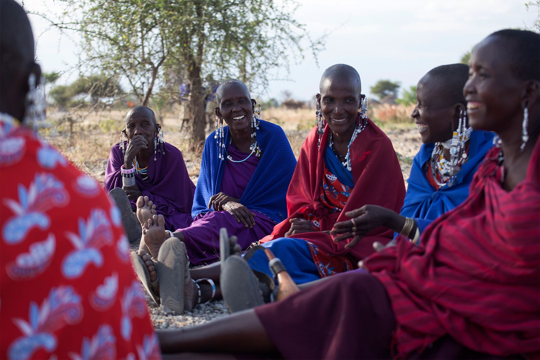 In Tanzania, the Kinapa (“We Carry Each Other”) women’s group of the Oltukai village meets beside the local primary school to discuss whether they should open a bank account. Throughout the past century, Maasai men have been the sole financial providers for their families, but with droughts and dwindling land access due to conservation, men are less able to provide. Many women have foregone societal norms and started businesses selling small goods, like petroleum jelly or snuff tobacco. In recent years, NGO