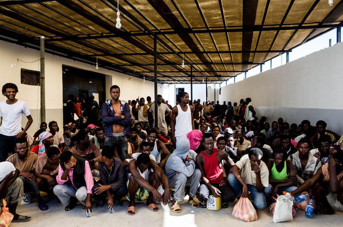 Migrants, mostly from West Africa, wait to receive daily food rations at the Triq al-Sikka detention center in Tripoli, Libya. Image by Peter Tinti. Libya, 2017.