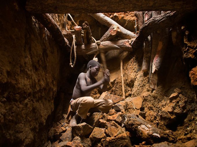 Nine-year-old Karim Sawadogo swings a pick at the bottom of a 40-foot pit at Kouékowéra. Image by Larry C. Price. Burkina Faso, 2013.