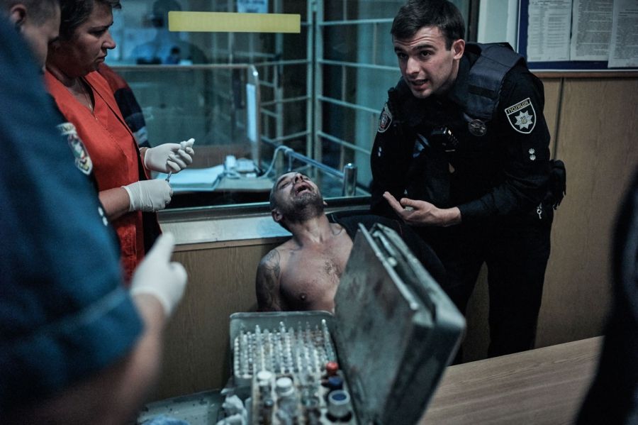 Lt. Vlad Fisotchenko helps paramedics calm down an aggressive intoxicated drug user. Image by Misha Friedman. Ukraine, 2016. 