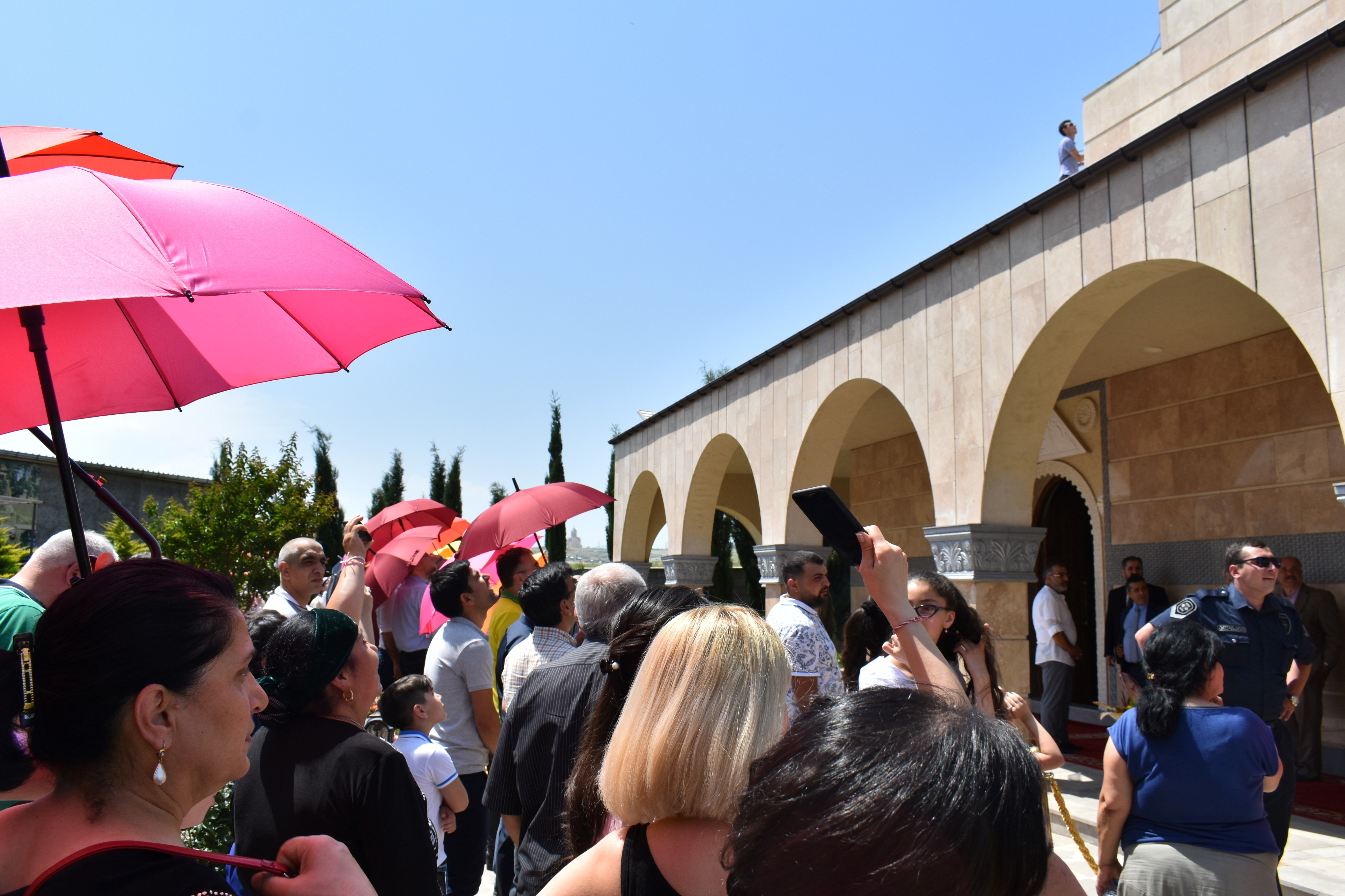 Yezidis gather in the temple courtyard in Tbilisi for Tawafa Ezid, anxiously looking on as a young man climbs the cupola to raise a flag. Image by Kaitlyn Johnson. Georgia, 2019.