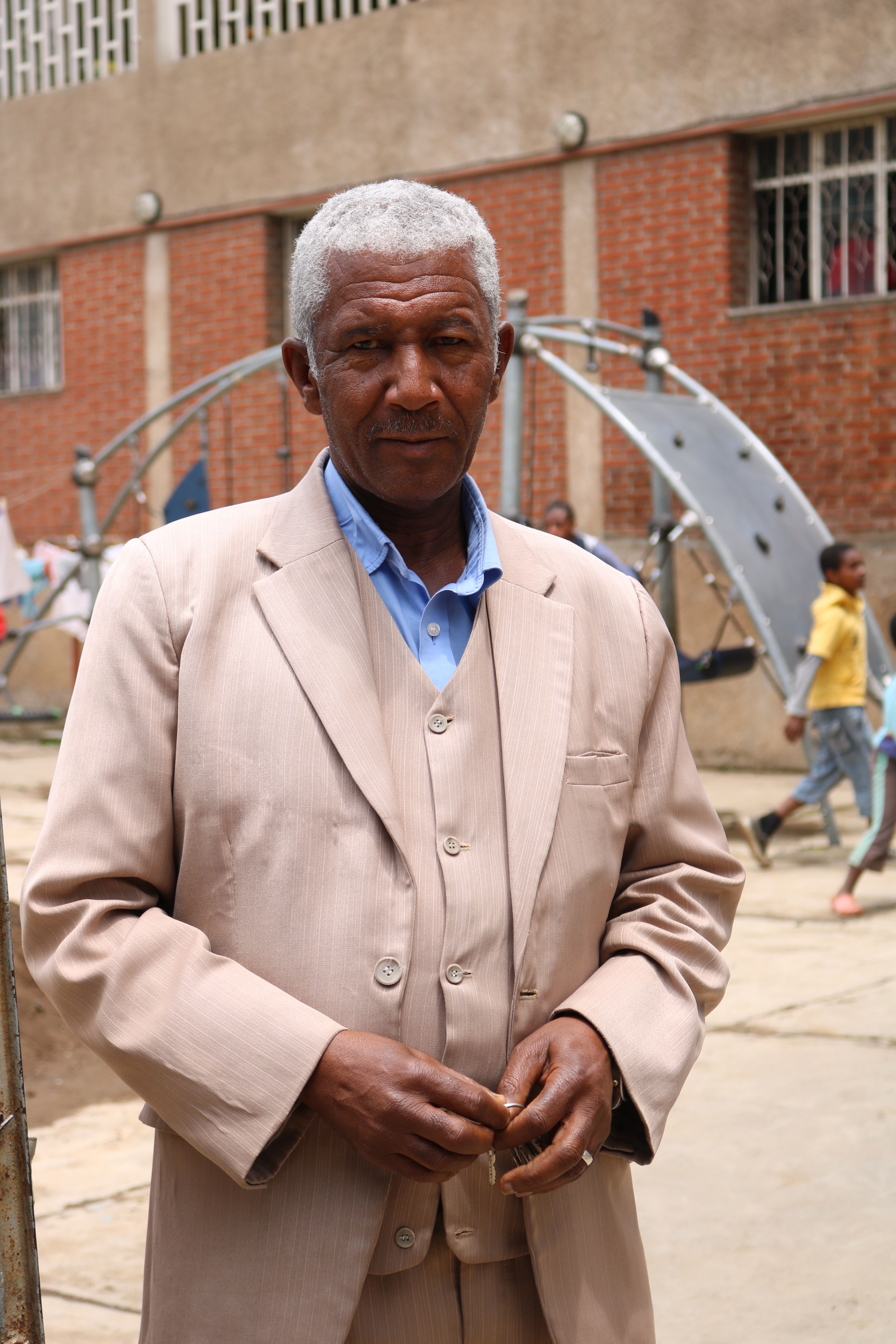 The director of Kidana Mehert Children's Home, Ato Assefa Kfile, poses for a picture in front of the playground located in Addis Ababa. Ato Assefa Kfile has worked closely with Sister Lutgarda to run the orphanage after he took over in 1996. There are about 50 children ranging in age from newborn to 18. Photo by Abigail Bekele. Ethiopia, 2018.

