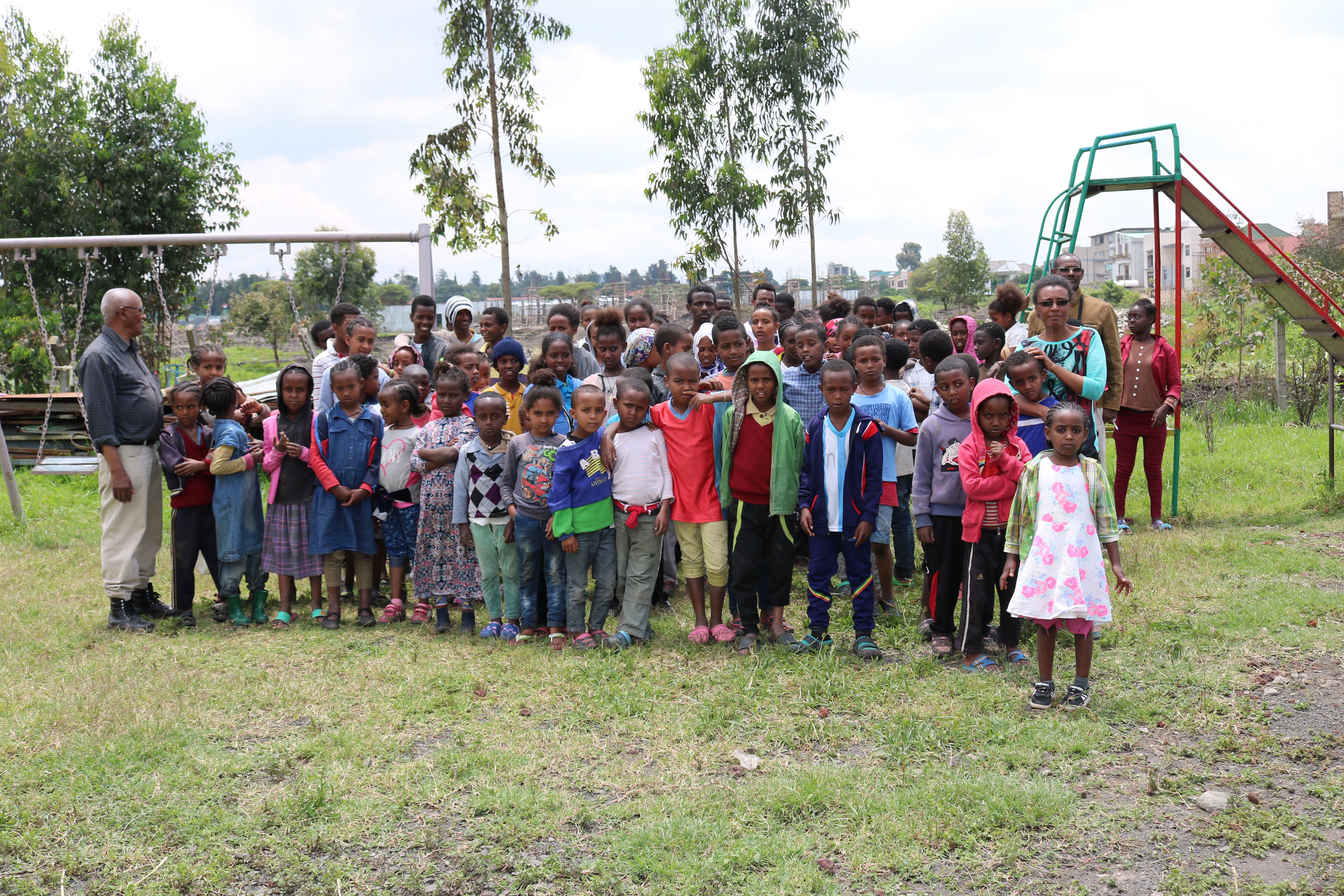 The children from Hanna Orphans Home pose for a group picture in front of their playground. These children are provided with homes that allow them to live together and build a community with one another. The orphanage helps children who lost their parents to HIV/AIDS. Image by Abigail Bekele. Ethiopia, 2018.