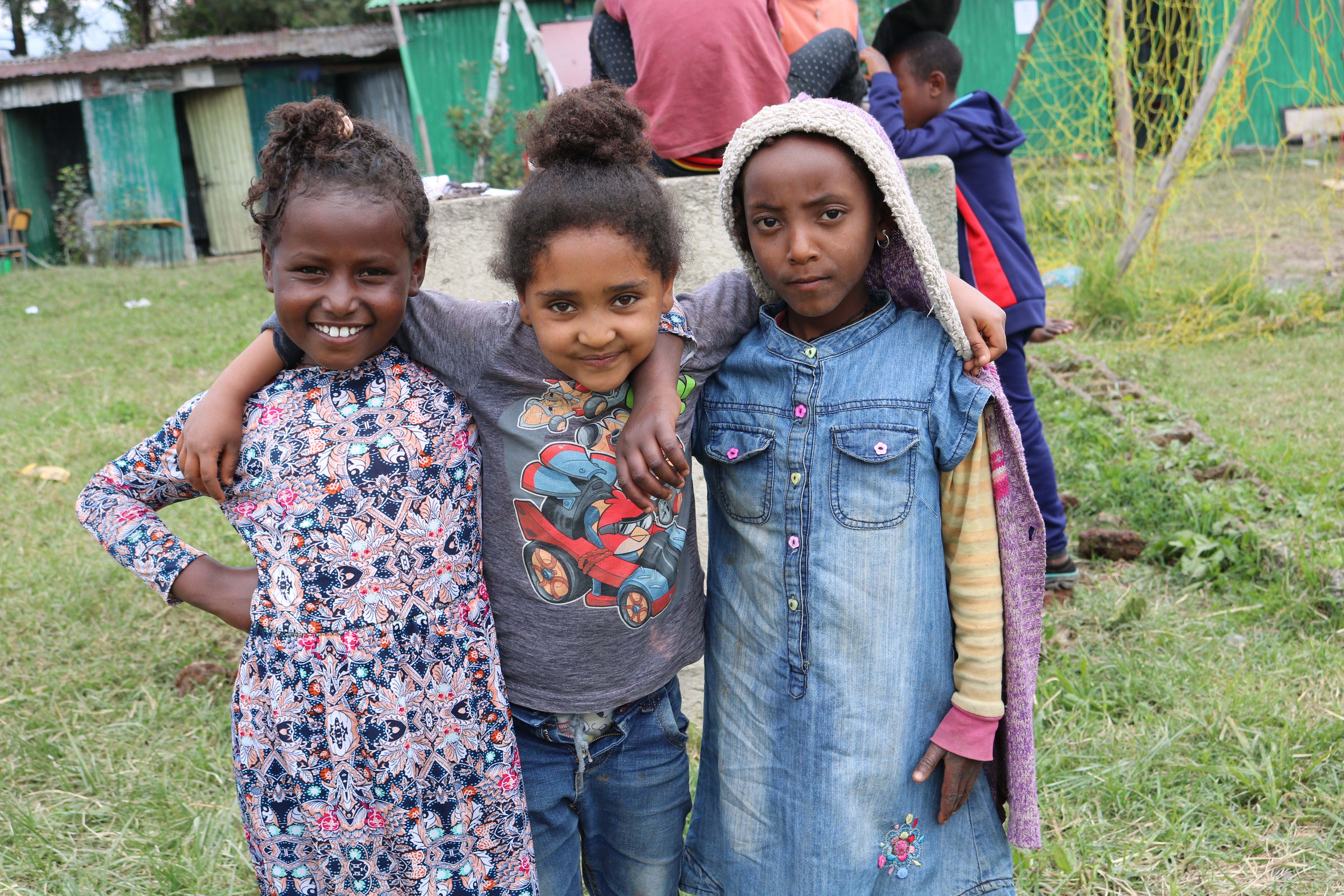 Sefel Berhanu, Mestawat Berihan, and Gennet Dereabu pose for a photo while they play on the playground after they finish lunch. They enjoy playing on the playground and board games. Image by Abigail Bekele. Ethiopia, 2018.