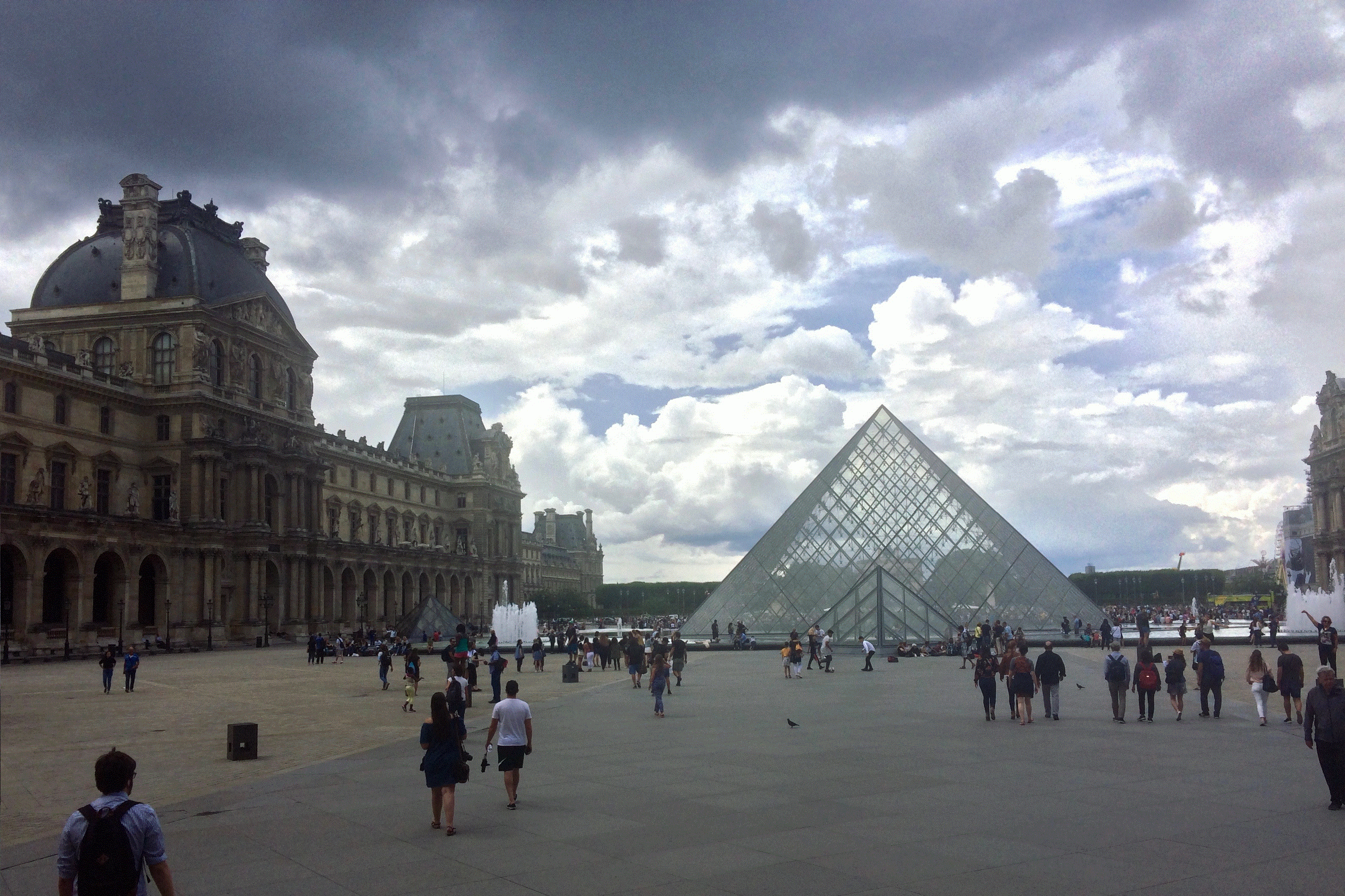 "Ominous rain clouds sweep across a Parisian sky. The glass pyramid of the Louvre rises up to meet the storm." Image and text by Liam Kennedy. France, 2017.