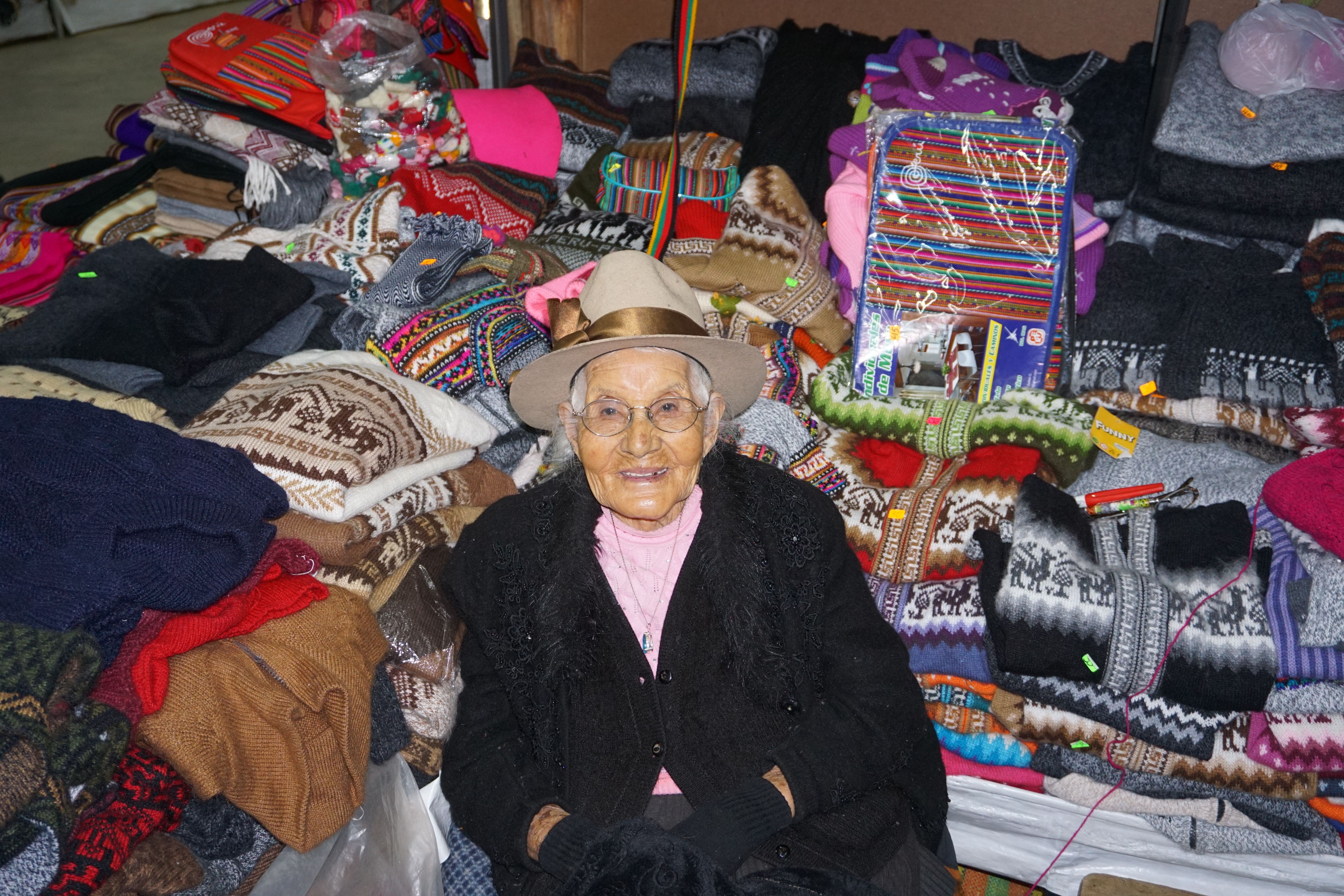 Ludmila Román Iparraguirre, a survivor of the 1941 flood, sitting in her daughter's shop at the artisan market in Huaraz. Image by Audrey Fromson. Peru, 2019.