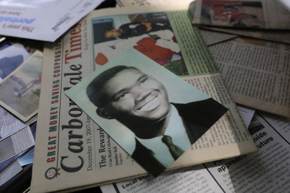 A 1967 portrait of a Milton L. McDaniel Sr. sits on other photos and newspaper clippings of him when he was younger, Sunday, Aug. 2, 2020, in Carbondale, Ill. After graduating from high school and getting injured while playing basketball, he went to work on the railroad in southern Illinois. He says, as the only Black man on a full crew, he was often discriminated against, being turned away from restaurants in some towns known as "sundown towns," while his white coworkers were served. Image by Wong Maye-E/AP Photo. United States, 2020.