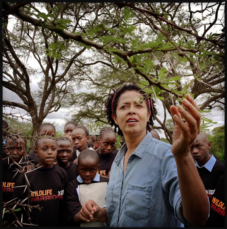 Science Leader, Kenya: CEO, conservationist, advocate: Paula Kahumbu runs the Kenyan conservation group WildlifeDirect. Kahumbu describes to city teenagers visiting Nairobi National Park the interplay between species: how ants help a native acacia tree defend itself against herbivores such as giraffes and rhinos. Image by Lynn Johnson. Kenya, 2019.