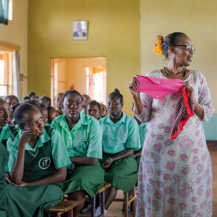 Community Activist, Kenya: After her family accepted her ardor for learning, Elizabeth Pantoren earned a doctorate and became an officer for a conservancy group and a champion of girls’ independence. Today’s exhortation, as she shows a Karare class a reusable sanitary pad holder: No girl should ever have to miss school because of her period. Image by Lynn Johnson. Kenya, 2019.