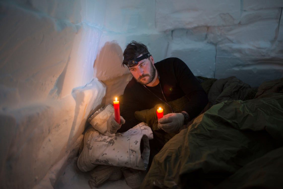 Canadian soldier Master Bombardier Jonathan Caron Corriveau holds survival candles that will be his only source of heat in an igloo he built on an Arctic operations advisers course. Soldiers learn from Inuit instructors how to build and sleep in improvised survival shelters at the Crystal City training area near Resolute Bay, where temperatures at times were as low as -50C (-58 F) with the windchill. Image by Louie Palu / Zuma Press. Canada, undated. 