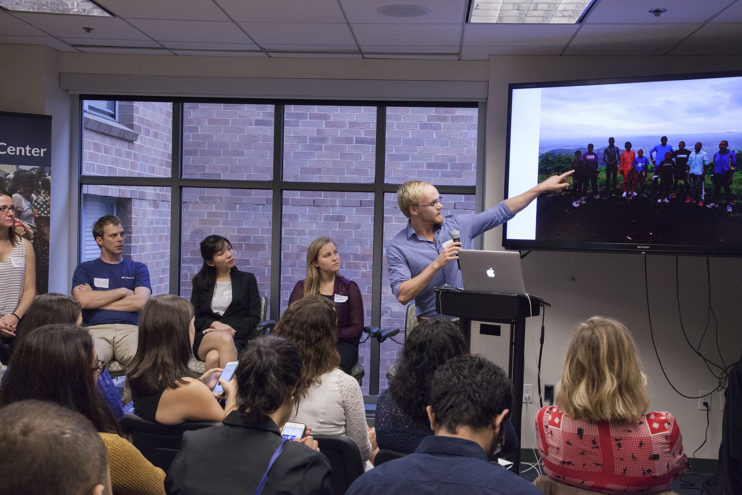 Kent State University fellow Daniel Socha presents his project on a youth running program in Eastern Congo. On the left, listening before presenting her own project on children's home is El Salvador is SIU Carbondale fellow Kayli Plotner. Image by Jin Ding. Washington, D.C., 2016.