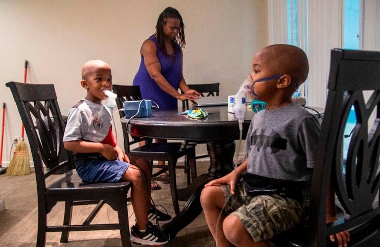 Vantisha Williams, waits for her twin sons Jeremiah, left, and Jonathan, right, to finish nebulizer treatments for asthma at their home in Bayboro Thursday, Aug. 20, 2020. Eastern North Carolina has more people making trips to hospital emergency departments for asthma treatments than in any other part of the state, researchers at East Carolina University reported. Image by Travis Long / The News & Observer. United States, 2020.
