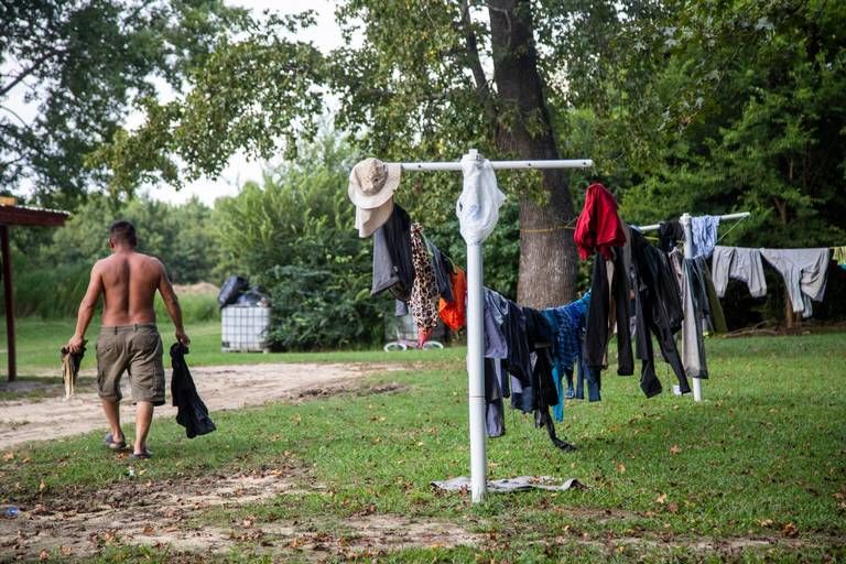A farmworker carries dried clothes from a clothesline at a Johnston County farmworker camp Thursday August 27, 2020. Image by Travis Long. United States, 2020.