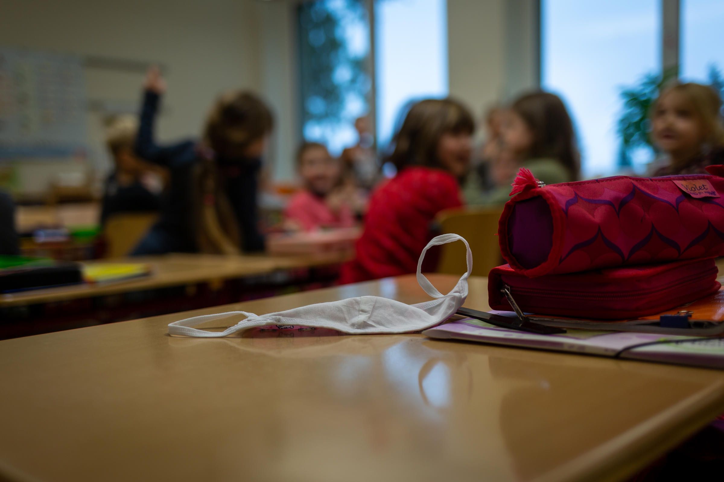 A mask sits on a desk at a primary school in Weimar, Germany. Students are required to wear masks in the hallways and on the playground but not while sitting in class. If coronavirus cases increase in the community or are found in the school, then tighter restrictions are implemented. Image by Ryan Delaney / St. Louis Public Radio. Germany, 2020.