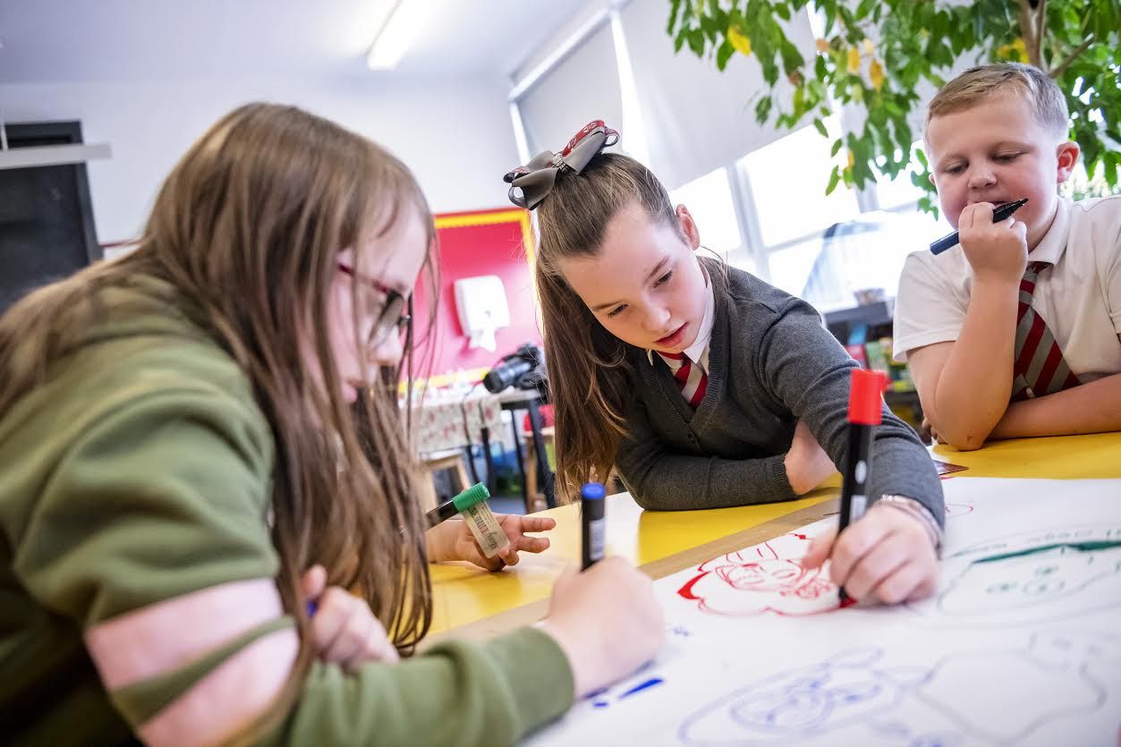 Summer McGeorge, 8, of Bridgeton, left, and Erin Patterson, 10, of Bridgeton, center, draw original characters while taking part in an art session as Mark Cleary, 9, of Bridgeton, right, looks on, Wednesday, Oct. 23, 2019 at Sacred Heart Primary School in Glasgow, Scotland. Image by Michael M. Santiago/Post-Gazette. United Kingdom, 2019.