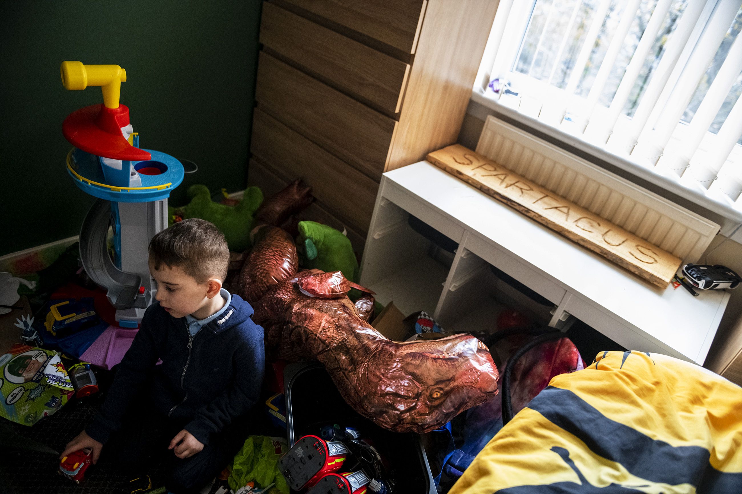 Spartacus Summers, 5, of Faifley, stares quietly out of his room while playing with a toy truck. Image by Michael Santiago. Scotland, 2019.