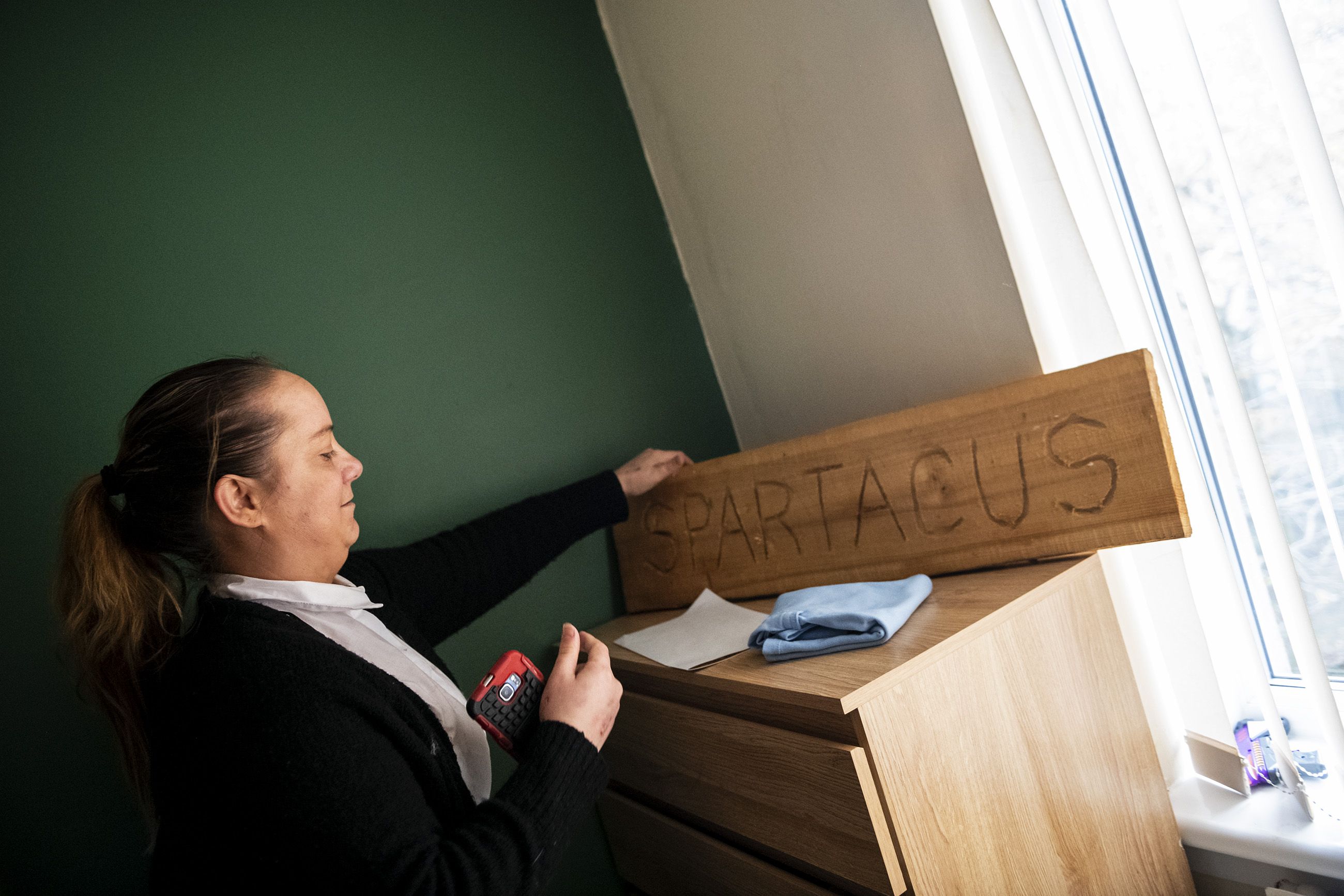 Natalie Muir fixes a wooden name plate with her son's name on it that she intends to hang on the wall of his room. Image by Michael Santiago. Scotland, 2019. 