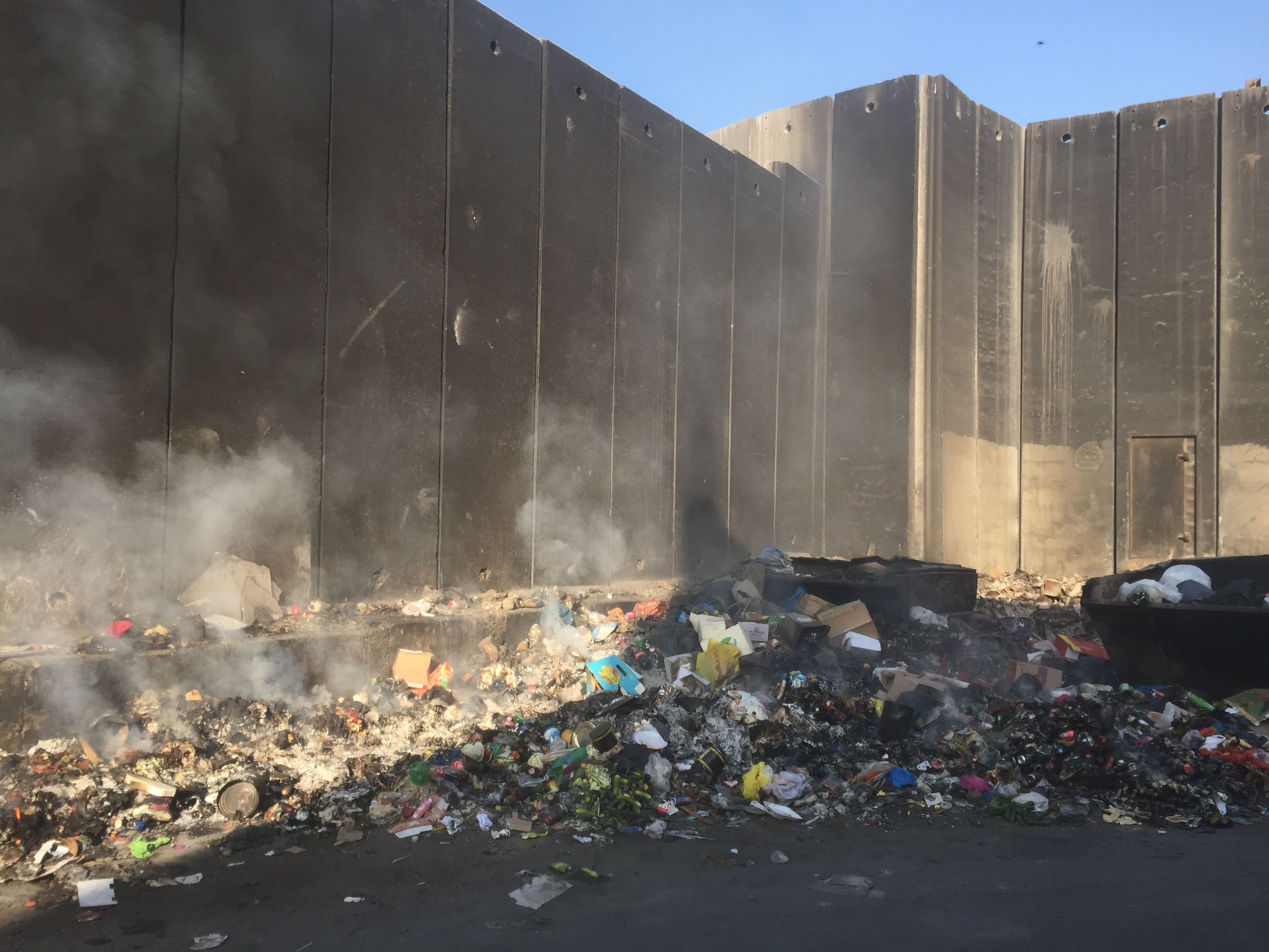 Rubbish burns on the Palestinian side of the illegal Israeli Separation Wall that cuts deep into Palestinian territory. Image by Matt Kennard. Palestine, 2016.