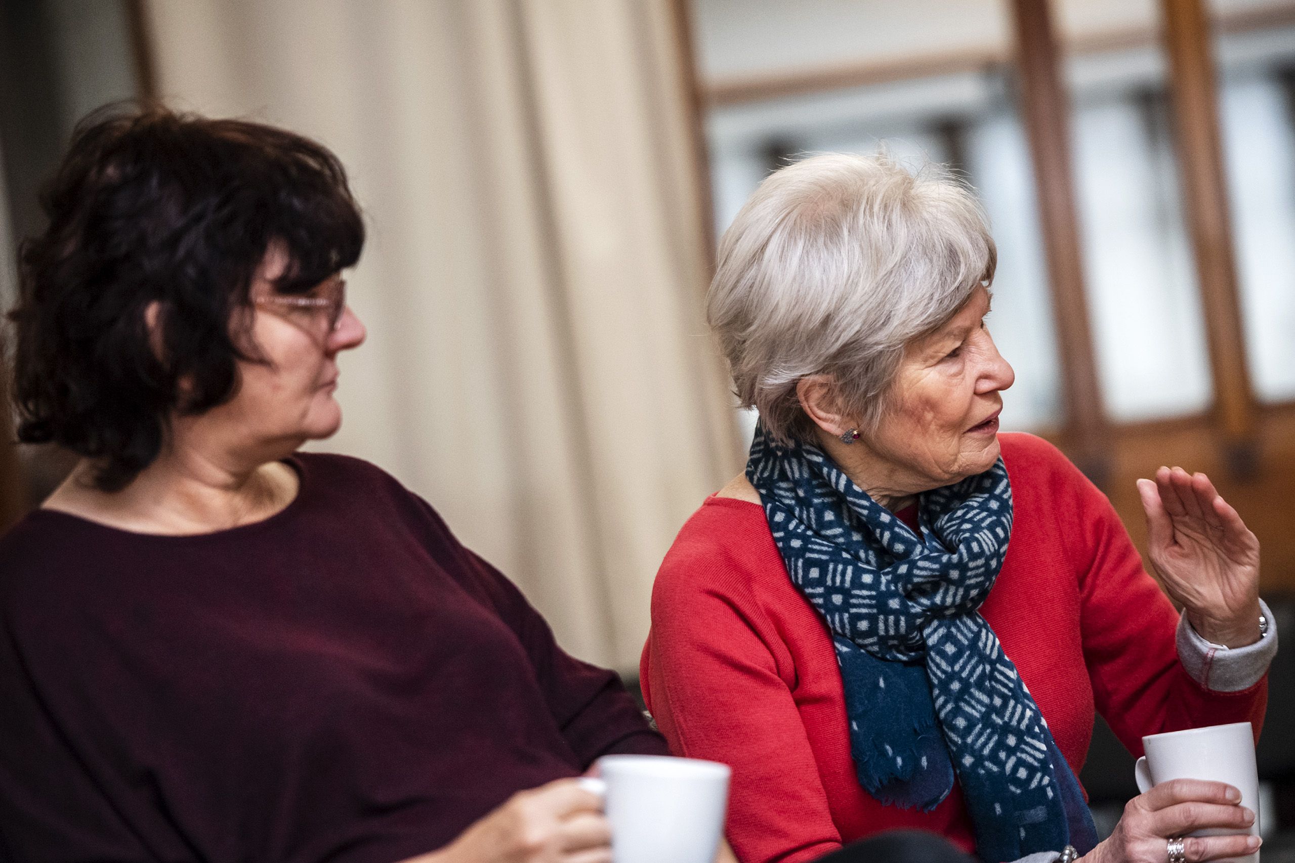 Caroline Mockford, of Govan a neighborhood of Glasglow, left, listens as Sandra Carter, of Edinburgh, speaks during the monthly Poverty Truth Community meeting at The Pyramid at Anderston. Image by Michael Santiago. United Kingdom, 2019.