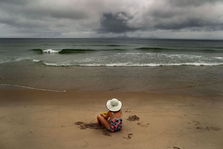 Salome Verkoville, a 10 year-old girl from Boston, sits on Nauset Beach as a storm rolls in. Image by John Tlumacki. United States, 2019.