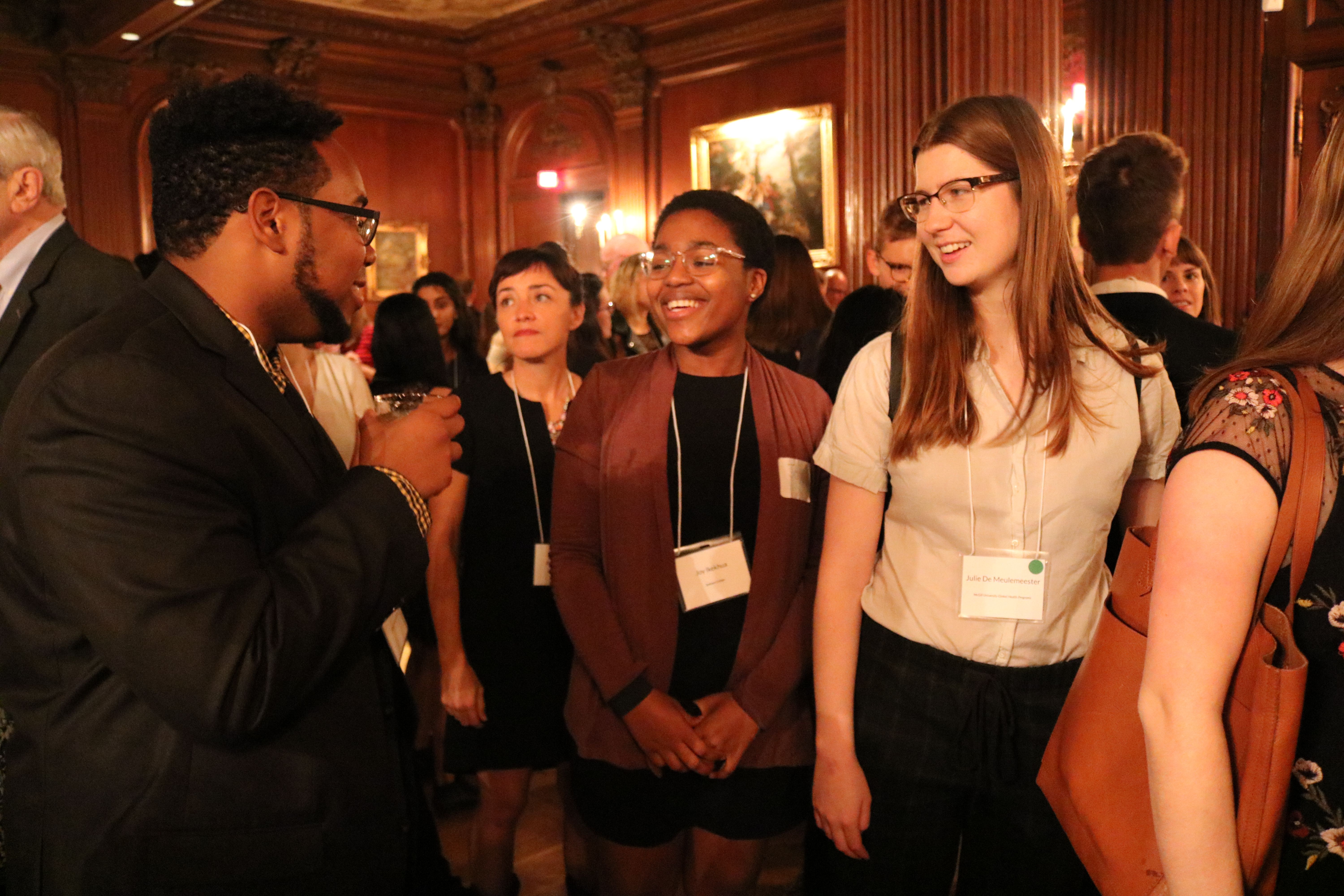 Student fellows Jonathan Custodio, Joy Ikekhua, and Julie De Meulemeester at the evening dinner. Behind them is Pulitzer Center grantee Allison Shelley. Image by Karena Phan. United States, 2018.