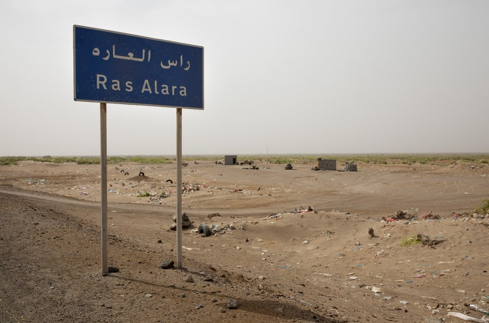 A road sign leading to the coastal village of Ras al-Ara, Lahj, Yemen. With its systematic torture, Ras al-Ara is a particular hell on the arduous, 900-mile (1,400 kilometer) journey from the Horn of Africa to oil-rich Saudi Arabia. Image by Nariman El-Mofty. Yemen, 2019.