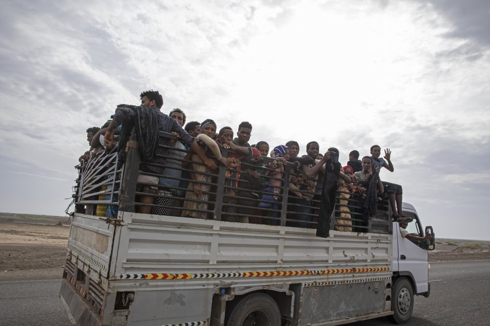 Ethiopian migrants who had just arrived in Yemen from Djibouti stand in the back of a pickup truck to be taken to desert compounds known in Arabic as "hosh," in Ras al-Ara, Lahj, Yemen. "Out of every thousand, 800 disappear in the lockups," said a humanitarian worker monitoring the flow of migrants. Image by Nariman El-Mofty. Yemen, 2019.