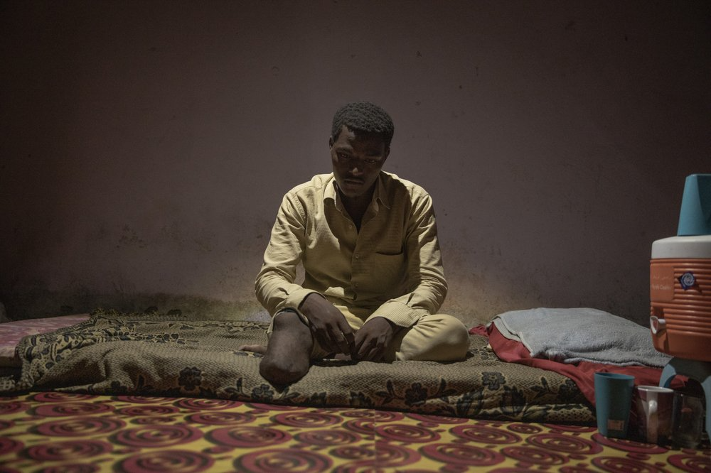 17-year-old Ethiopian migrant Abdul-Rahman Taha, shows his amputated leg, at his home, in Basateen, a district of Aden, Yemen. When he landed at Ras al-Ara, traffickers took him and 50 other migrants to a holding cell, demanding phone numbers. Taha couldn't ask his father for more money so he told them he didn't have a phone number. One night, a captor beat his right leg with a steel rod. Taha passed out and was dumped in the desert with three dead migrants by traffickers. Image by Nariman El-Mofty. Yemen, 2019.