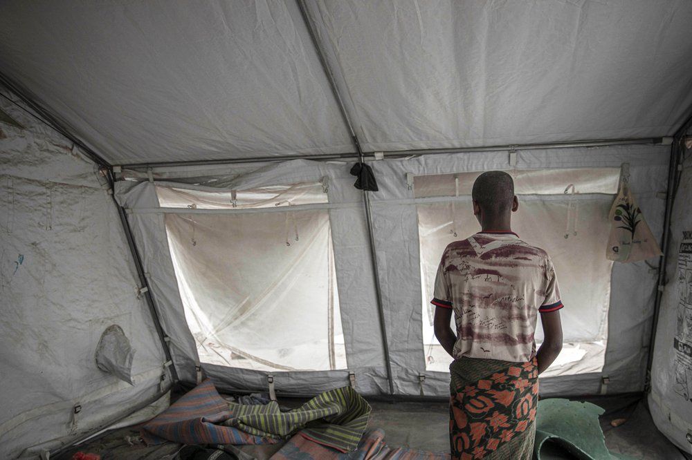 15-year-old Nogos stands in a tent at the "22nd May Stadium" where he took shelter with other migrants, in Aden, Yemen. Image by AP Photo/Nariman El-Mofty. Yemen, 2020.