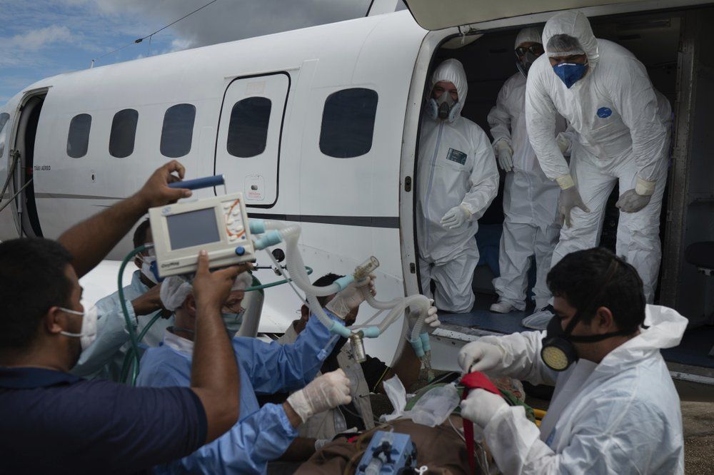 Health workers prepare to move 89-year-old COVID-19 patient Sildomar Castelo Branco into an aircraft as he is transferred from Santo Antonio do Içá to a hospital in Manaus, Brazil, Tuesday, May 19, 2020. Image by AP Photo/Felipe Dana. Brazil, 2020.