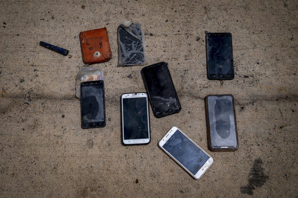 Phones and other items are placed on the ground by police officers as they inspect a boat where 15 Malians were found dead adrift in the Atlantic on Thursday, Aug. 20, 2020, in Gran Canaria island, Spain. Image by Emilio Morenatti/AP Photo. Spain, 2020.