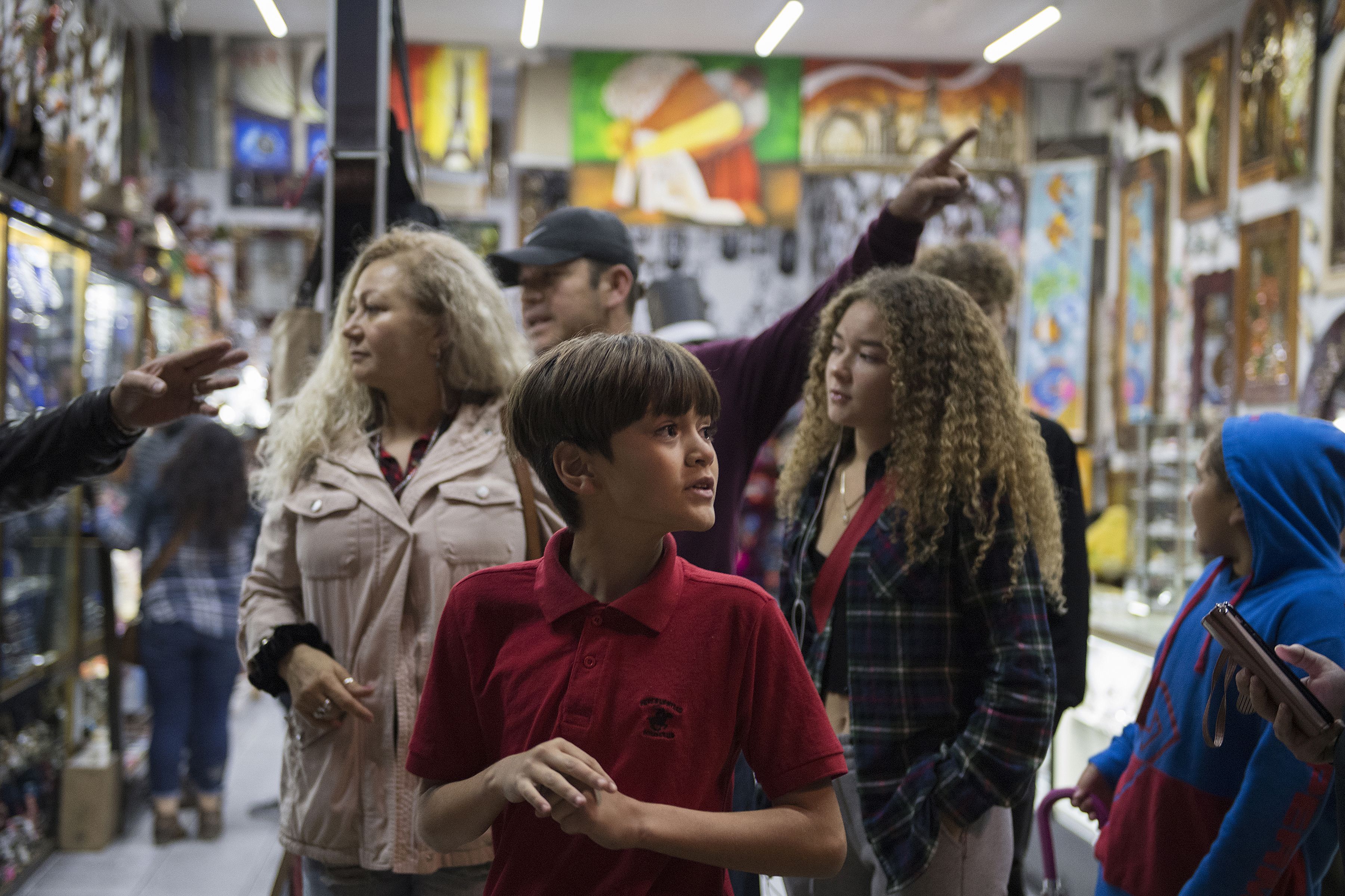 Edward Flores, 12, foreground, joins members of his family as they get directions from a shop owner on Avenida Revolucion in downtown Tijuana on Saturday, Nov. 30, 2019. With money in short supply and safety concerns for the children, the family rarely gets to make shopping trips. Image by Amanda Cowan. Mexico, 2019.