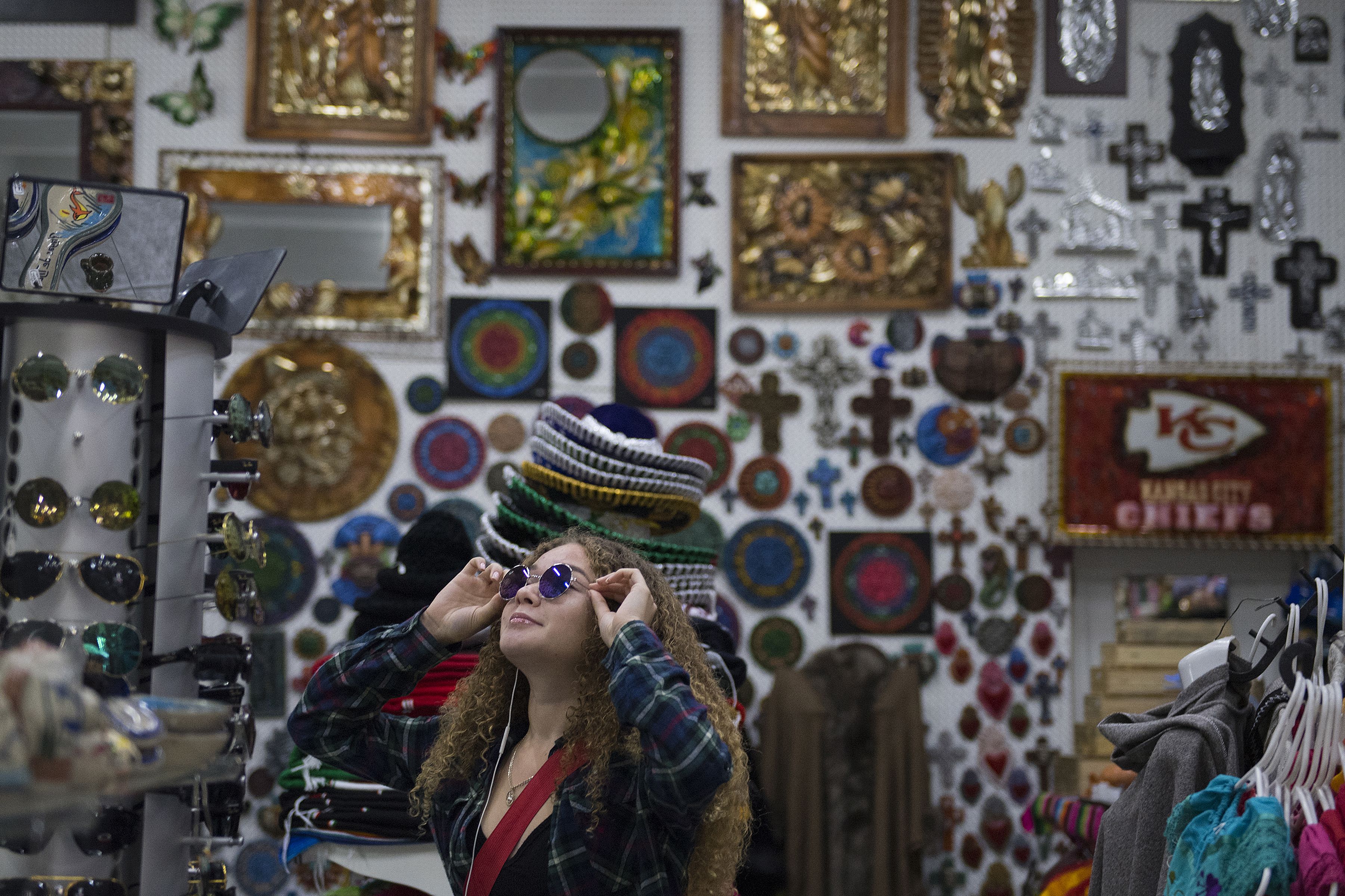 Kennedy Flores tries on a pair of sunglasses while shopping in downtown Tijuana with her family Nov. 30. Image by Amanda Cowan. Mexico, 2019.