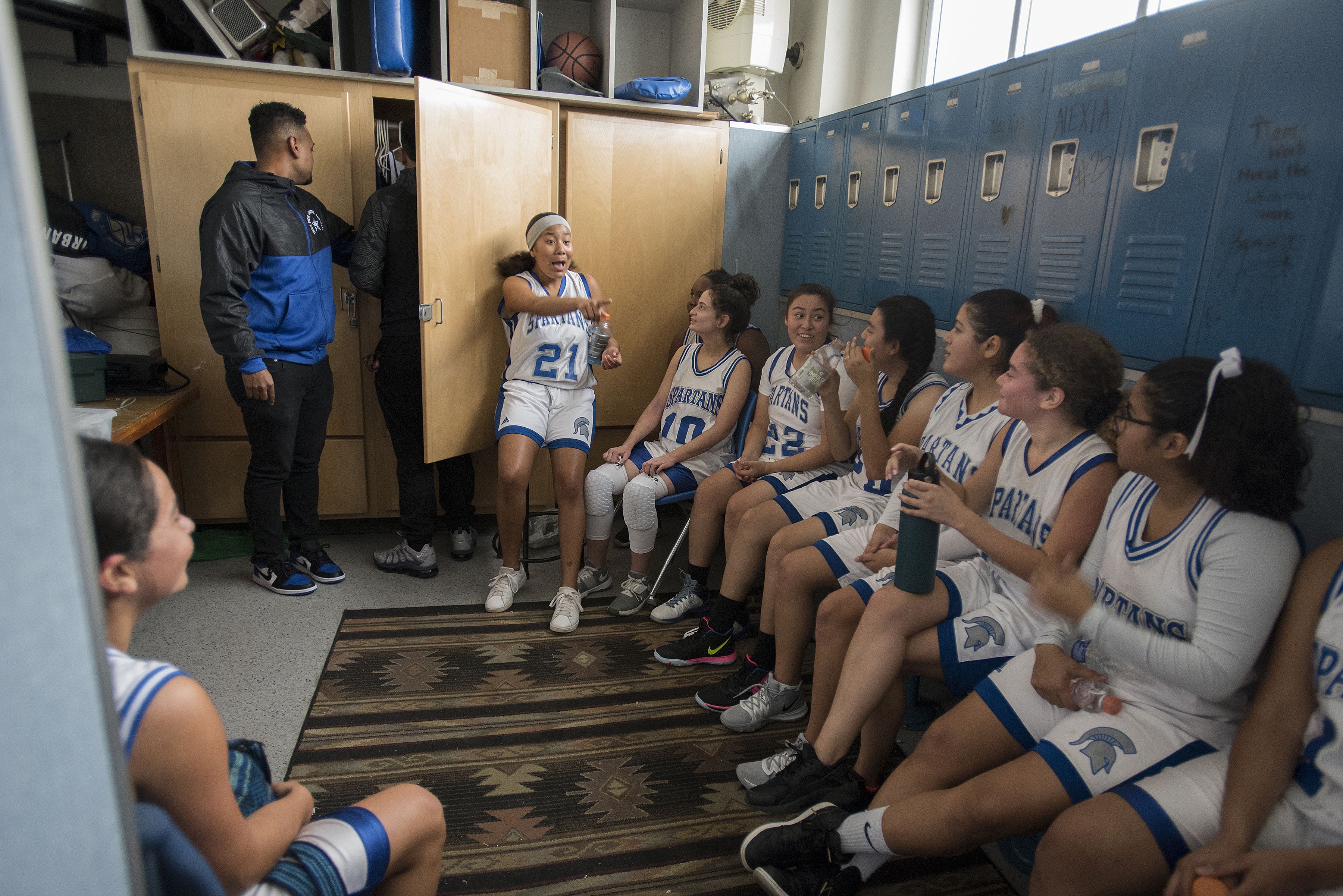 Kennedy Flores, 16, second from right, joins teammates in the locker room at halftime at Chula Vista High School on Nov. 27. Flores is one of the captains of her basketball team. Image by Amanda Cowan. United States, 2019.
