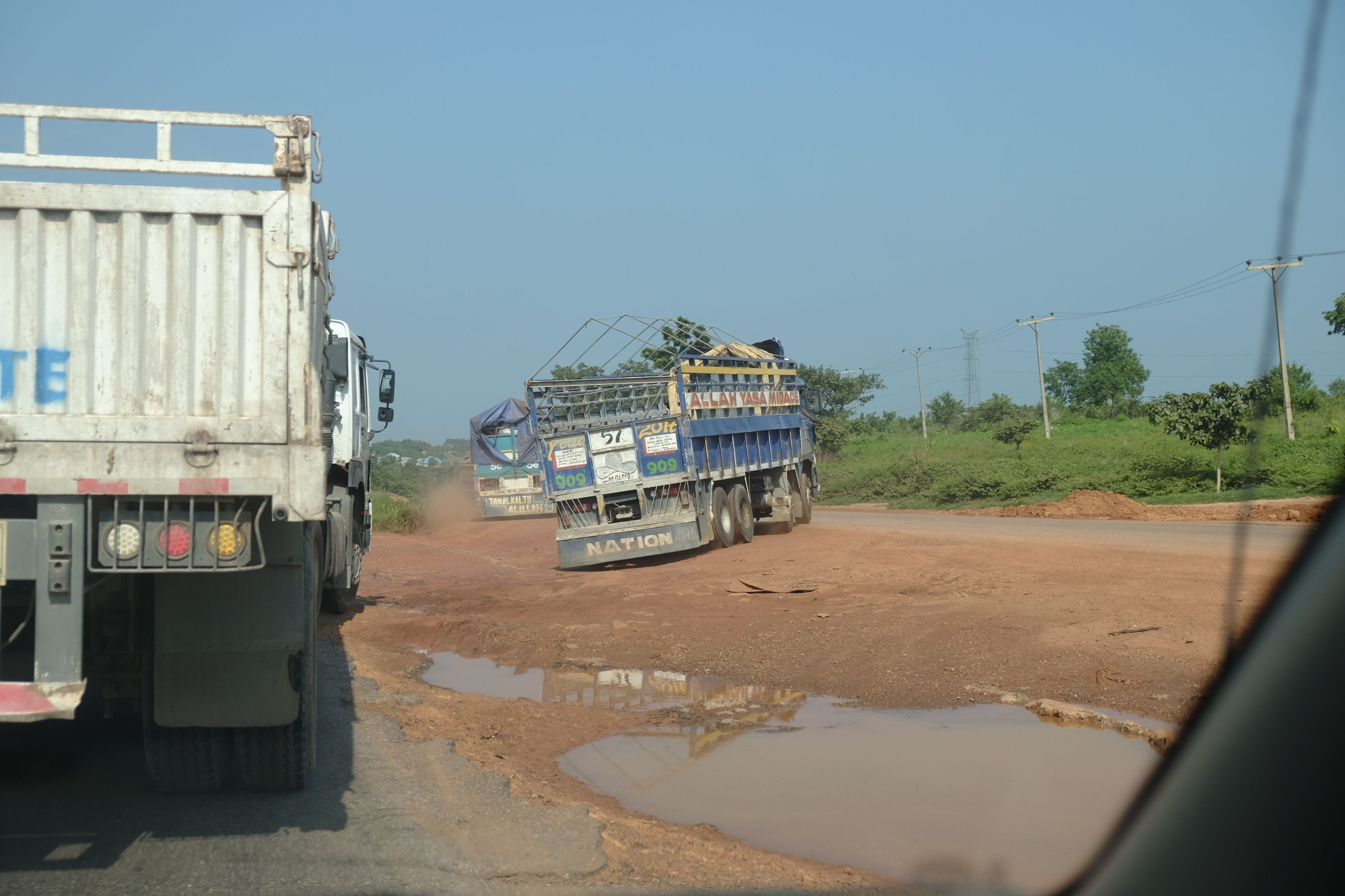 Trucks navigate a closed portion of the Abuja-Lokoja highway in Nigeria by crossing a water-filled median to the other lane. Image by T.R. Goldman. Nigeria, 2017.
