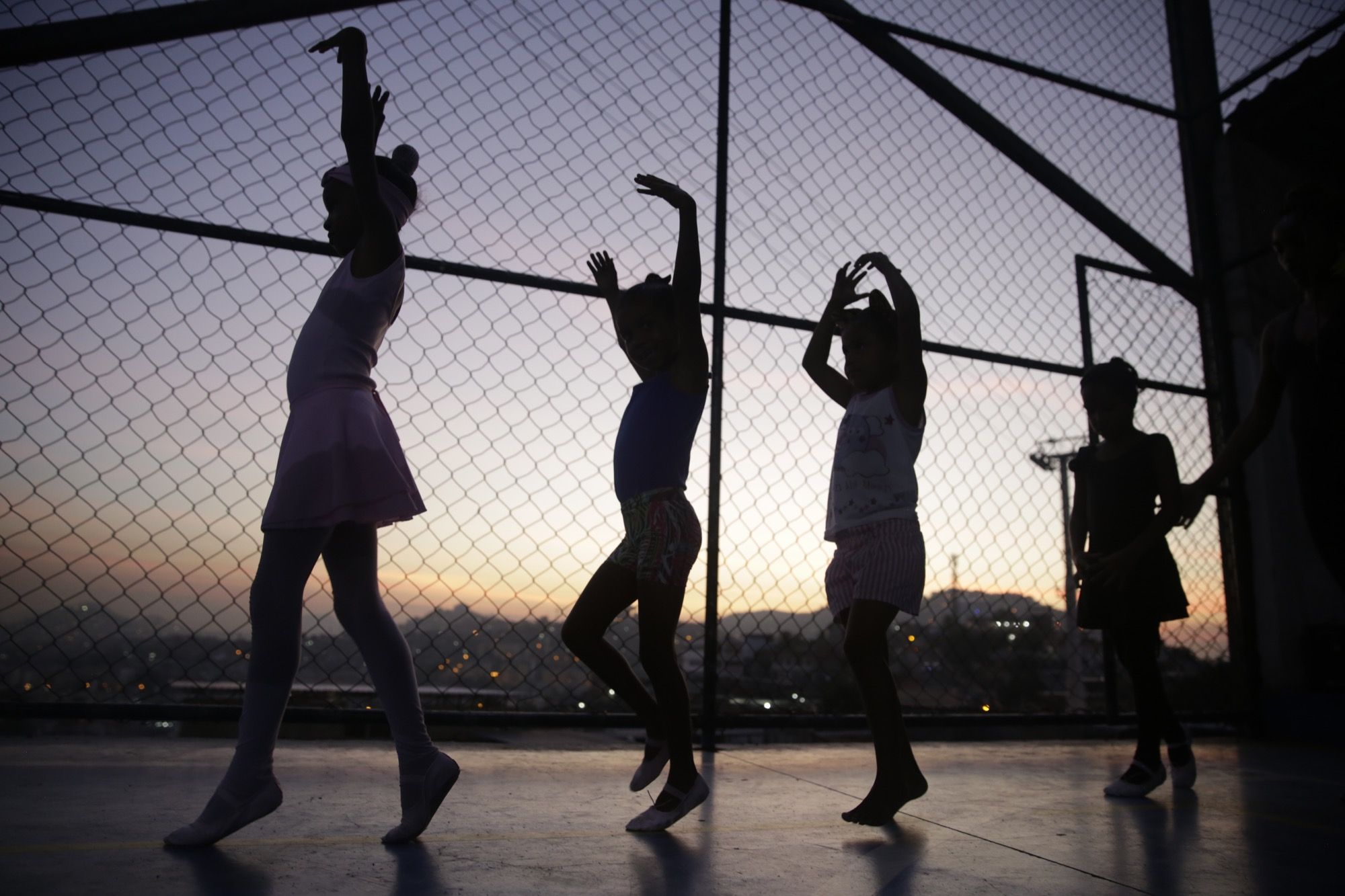 Young ballerinas rehearse at an outdoor sports court in the Morro do Adeus favela, Rio de Janeiro. Image by Frederick Bernas. Brazil, 2018.