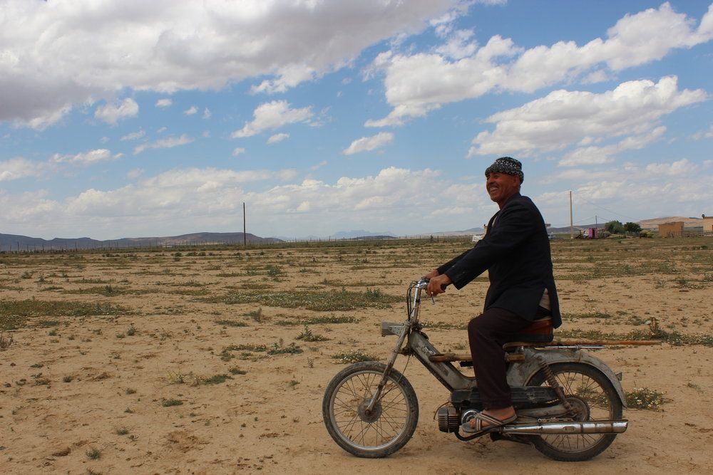 Azooz Ezzeen, 66, rides his motorbike outside his farm. Due to climate change, his children have chosen career paths outside of farming and sheepherding. Image by Yasmin Bendaas. Algeria, 2016.