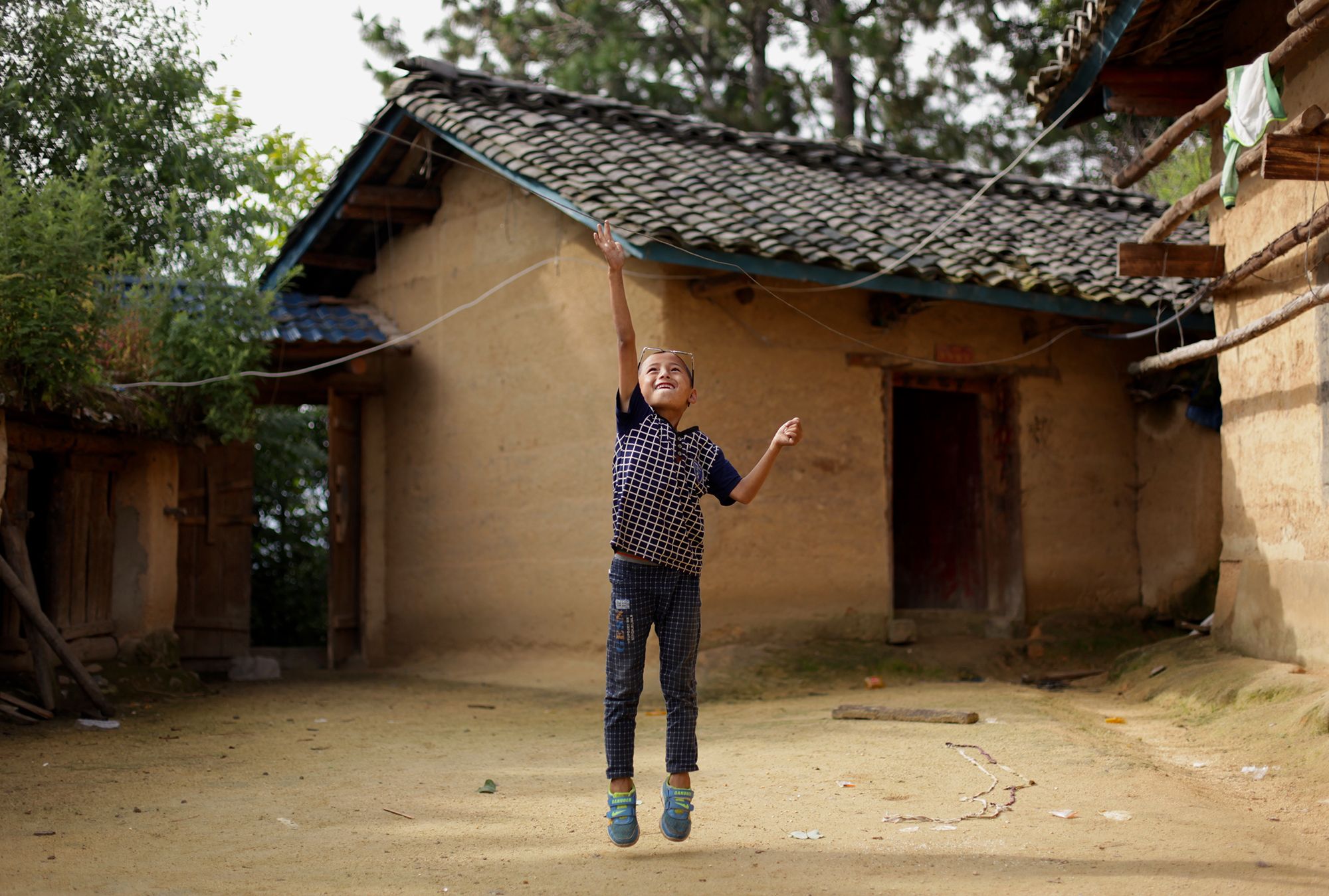 Eight-year-old Wang Jie plays in the courtyard of his family's farmhouse in Liangshan prefecture, Sichuan province. Image by Max Duncan. China, 2016. 
