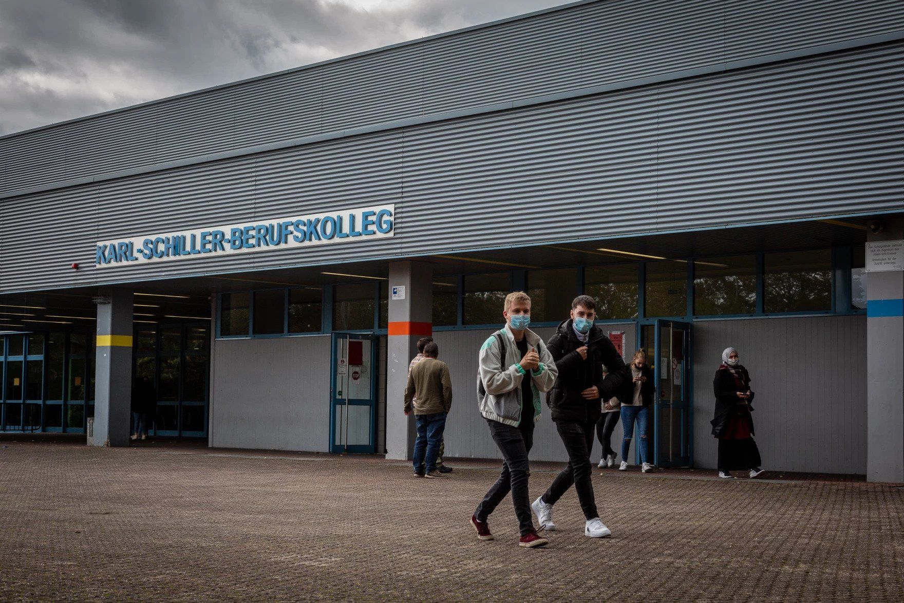 Students leave Karl-Schiller-Berufskolleg in Brühl, a secondary school outside Cologne, Germany. Students are required by the school to wear masks on schools grounds. Image by Ryan Delaney. Germany, 2020.