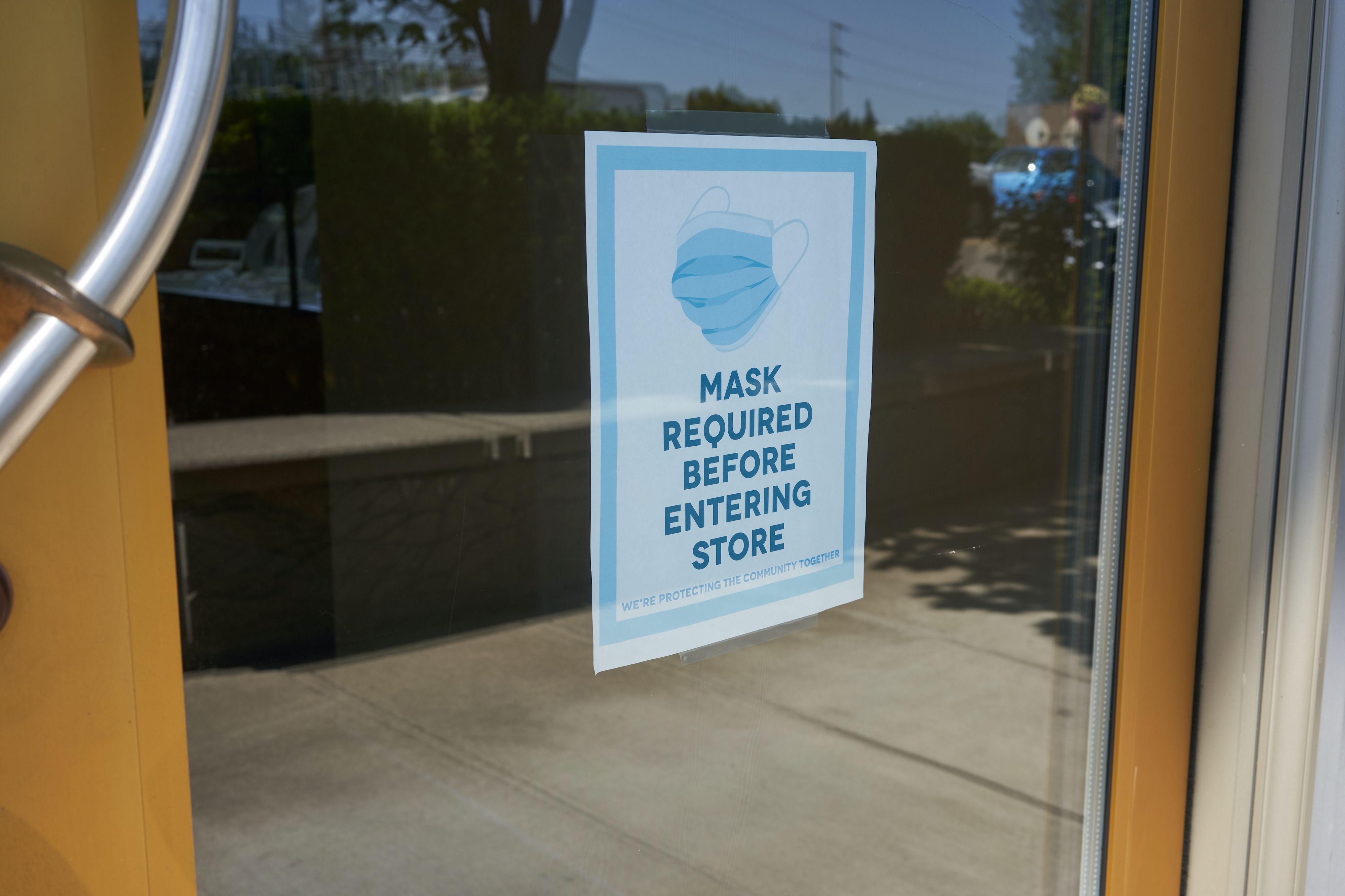 Mandatory mask policy signage at the entrance to a retail store in Oregon during the coronavirus pandemic. Image by Tada Images / Shutterstock. United States, 2020.