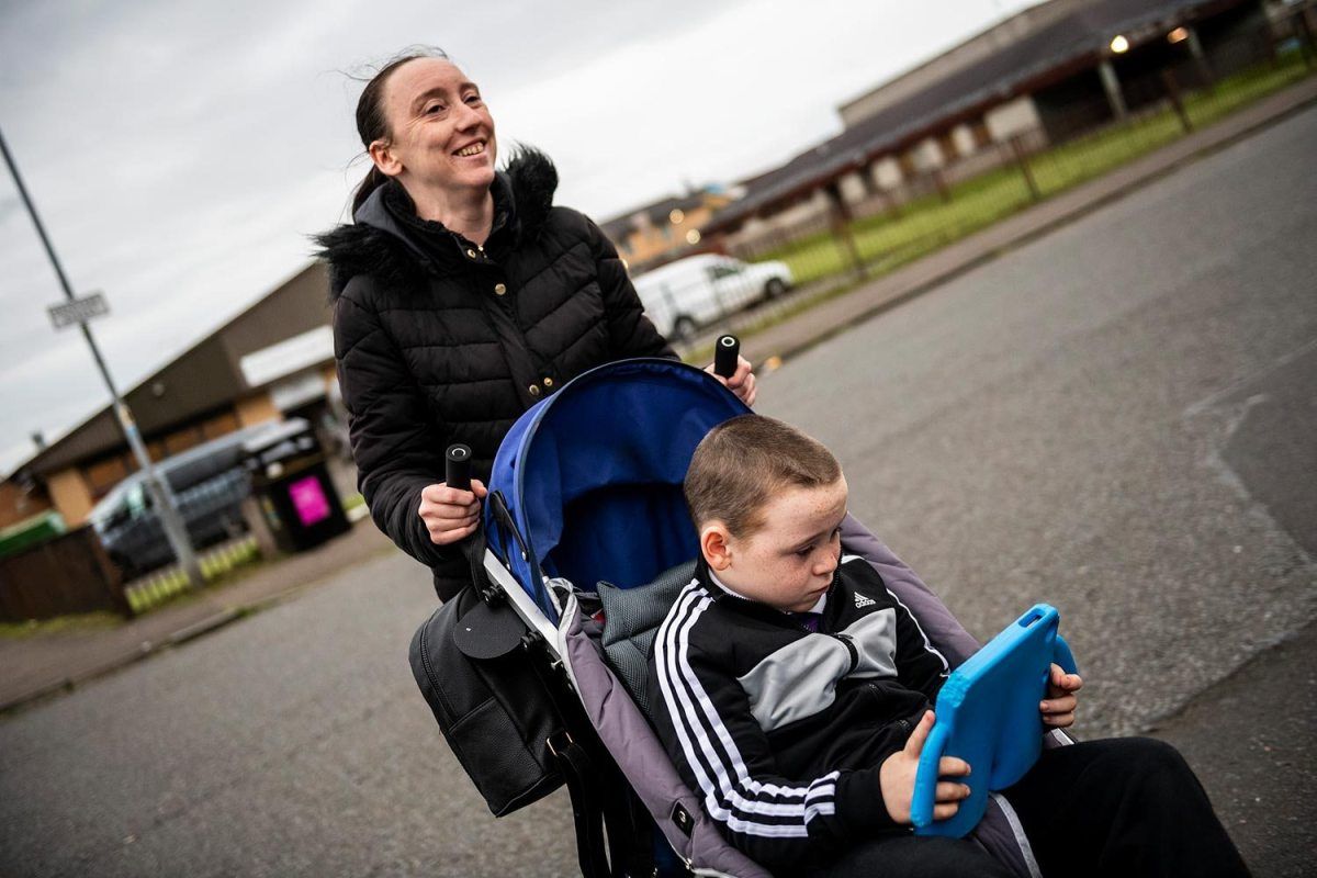Leanne Quigley, of Possilpark, a neighborhood in Glasgow, pushes her son David Crichton, 7, back home after leaving Possilpoint Community Centre. Image by Michael Santiago. United Kingdom, 2019.