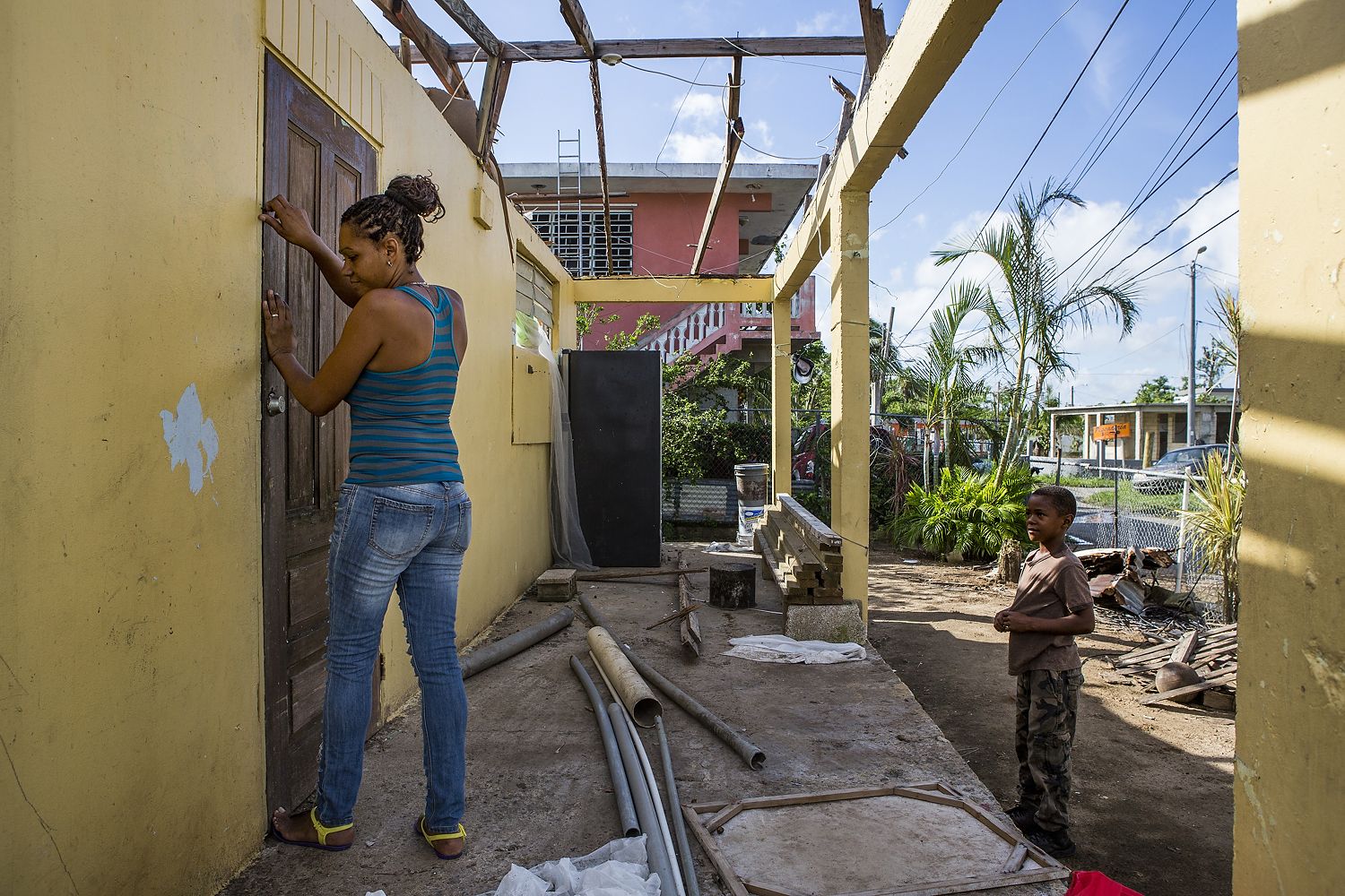 Rosalda Olma, a wife and mother to three kids, opens the front door to what remains of her home in Loiza. The entire home and contents were destroyed by the hurricane, and the family is living in a nearby school for the time being. “It’s hard getting used to these living conditions,” she said. “All five of us are trying to fit inside a single room.” Image by Ryan Michalesko. Puerto Rico, 2017.