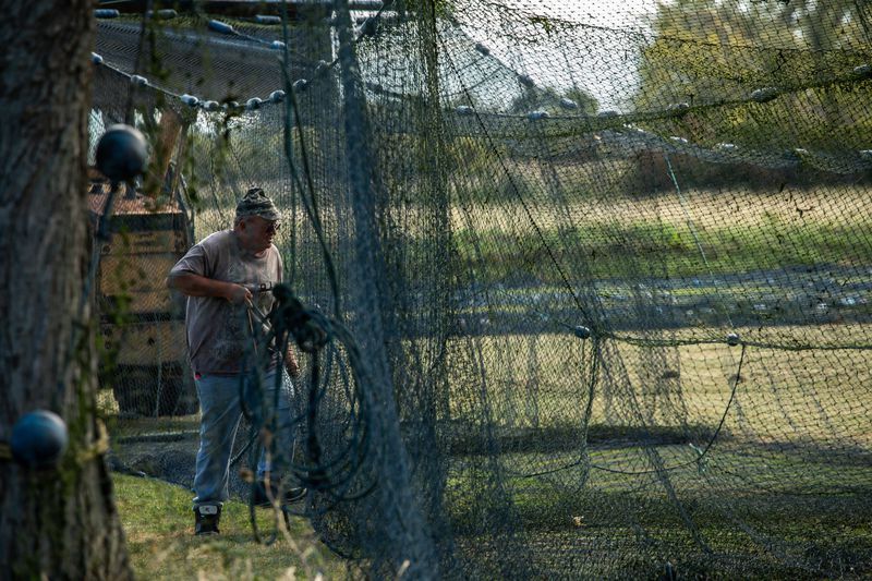 Ernie Thomas repairs the 20-ft. trap net at Whites Landing Fisheries in Sandusky, Ohio. He works for commercial fisherman Drew Koch and his father Dean Koch. Image by Zbigniew Bzdak. United States, 2019.