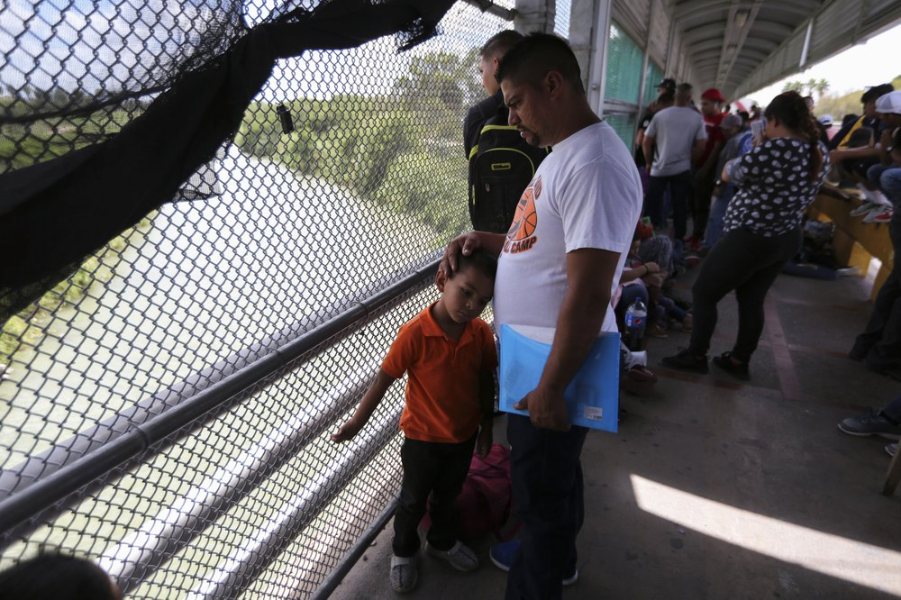 In this Oct. 10, 2019 photo, migrants wait for U.S. authorities to reopen a legal port of entry between Matamoros, Mexico, and Brownsville, Texas, after the bridge was closed briefly by U.S. authorities during a protest by migrants in Matamoros. Mexican gangs have adapted quickly to the new reality of masses of vulnerable migrants parking in the heart of their fiefdom, experts say, treating the travelers, often families with young children, like ATMs, ramping up kidnapping, extortion, and illegal crossings to extract money and fuel their empires. Image by Fernando Llano. Mexico, 2019.