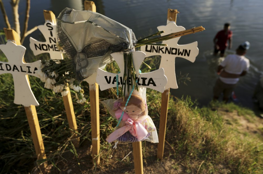 In this Oct. 11, 2019 photo, crosses covered with the names of people who have drowned trying to cross the river stand on the bank of the Rio Grande in Matamoros, Mexico. Migrants who make it this far, tell stories of being captured by armed bandits who demand a ransom: They can pay for illegal passage to the border, or merely for their freedom, but either way they must pay. Image by Fernando Llano. Mexico, 2019.