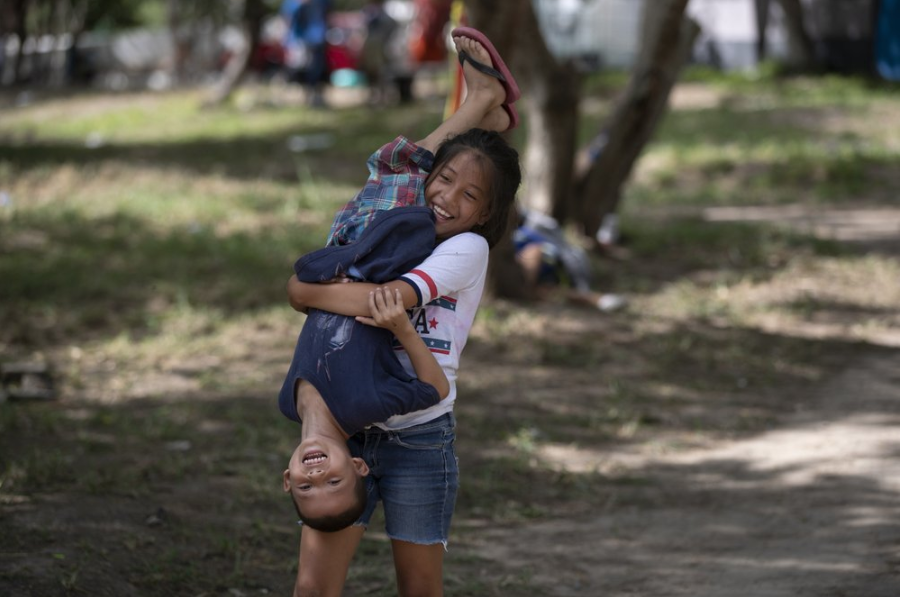 In this Oct. 11, 2019 photo, migrant children play in an area where other migrants set up camp near a legal port of entry bridge in Matamoros, Mexico. In years past, migrants seeking asylum in the United States moved quickly through this violent territory on their way to the U.S., but now due to Trump administration policies, they remain here for weeks and sometimes months as they await their U.S. court dates, often in the hands of gangsters who hold Tamaulipas state in a vice-like grip. Image by Fernando Llano. Mexico, 2019.