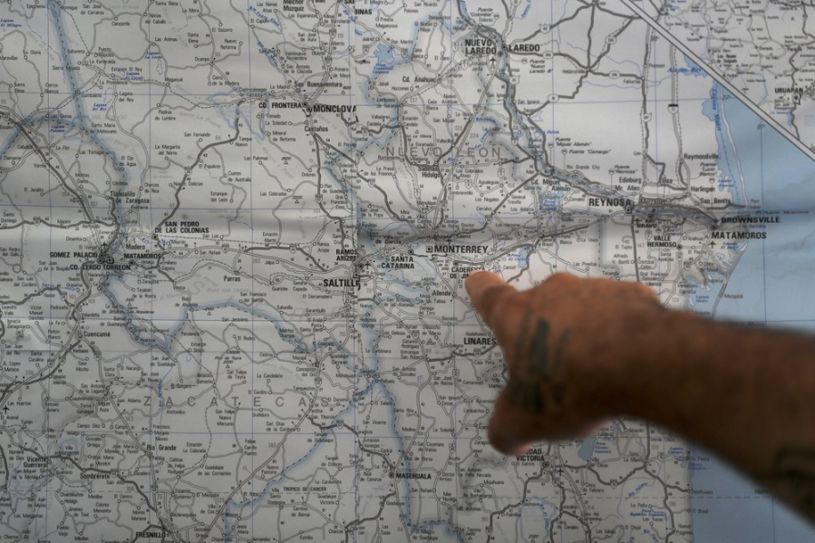 In this Oct. 10, 2019 photo, a Mexican migrant points to a map of U.S.-Mexico border cities, hanging on display at a migrant shelter in Reynosa, Mexico. The Mexican state of Tamaulipas used to be a crossroads. Its dangers are well known; the U.S. has warned its citizens to stay away, assigning it the same alert level as war-torn countries such as Afghanistan and Syria. Image by Fernando Llano. Mexico, 2019.